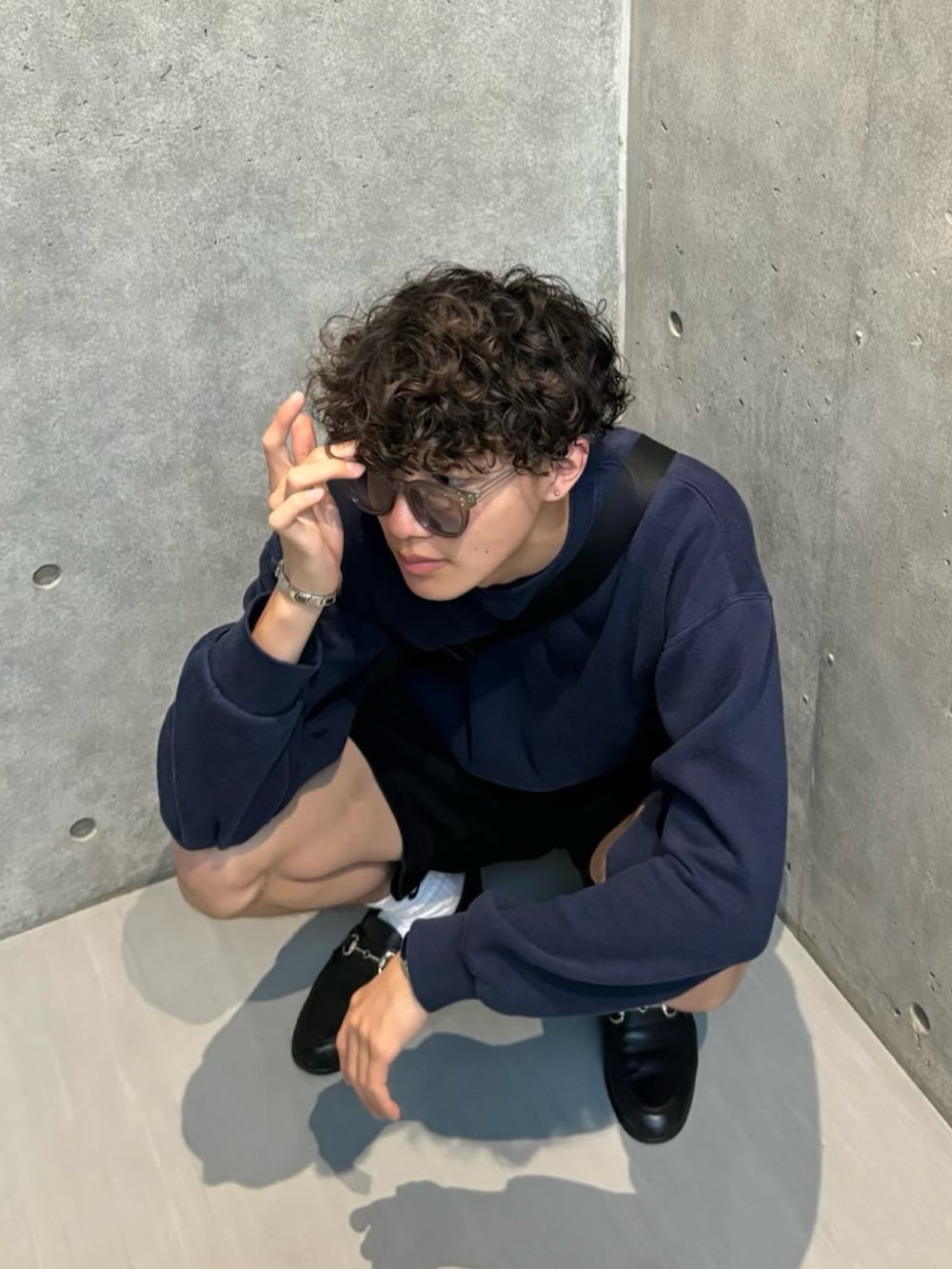 ブルー系のスウェット、ブラック系のパンツ、ブラック系のローファーを着用したメンズの春コーディネートの2枚目の写真