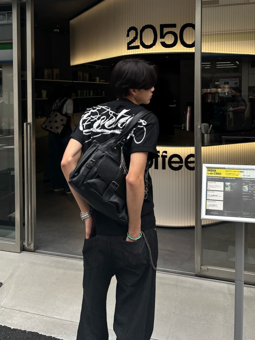 ブラウン系のショルダーバッグ、ブラック系のTシャツ/カットソー、ブラック系のデニムパンツを着用したメンズの夏コーディネートの3枚目の写真