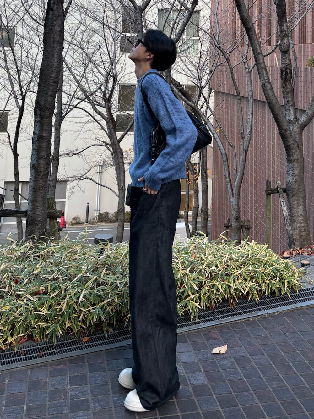 ブルー系のニット/セーター、ブラック系のデニムパンツ、ブラック系のスニーカーを着用したメンズの冬コーディネートの2枚目の写真