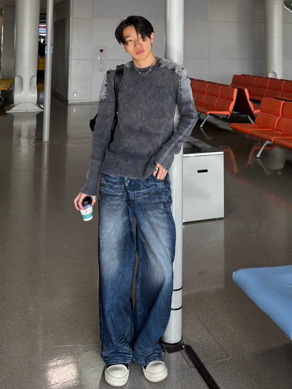 グレー系のニット/セーター、ブルー系のデニムパンツ、ブラック系のスニーカーを着用したメンズの冬コーディネートの2枚目の写真