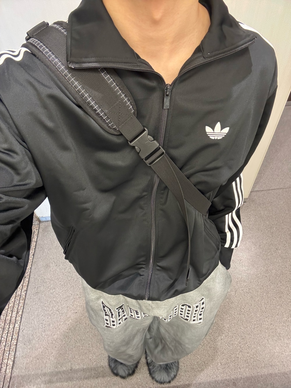 ブラック系のジャージ、ブラック系のボディバッグ/ウエストポーチ、グレー系のスウェットパンツを着用したメンズの春コーディネートの2枚目の写真