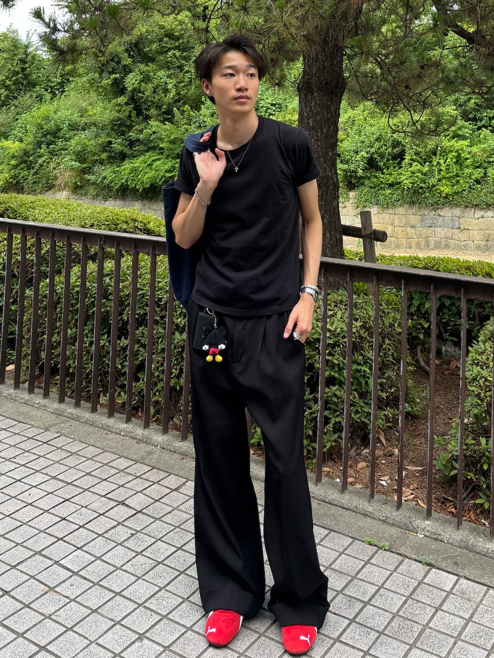 ブラック系のTシャツ/カットソー、ブラック系のスラックス、レッド系のスニーカーを着用したメンズの夏コーディネートの2枚目の写真