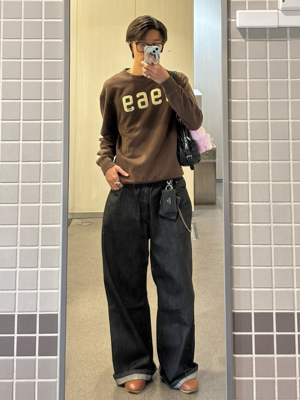 ブラック系のデニムパンツ、ブラウン系のスウェット、ブラウン系のスニーカーを着用したメンズの秋コーディネートの2枚目の写真