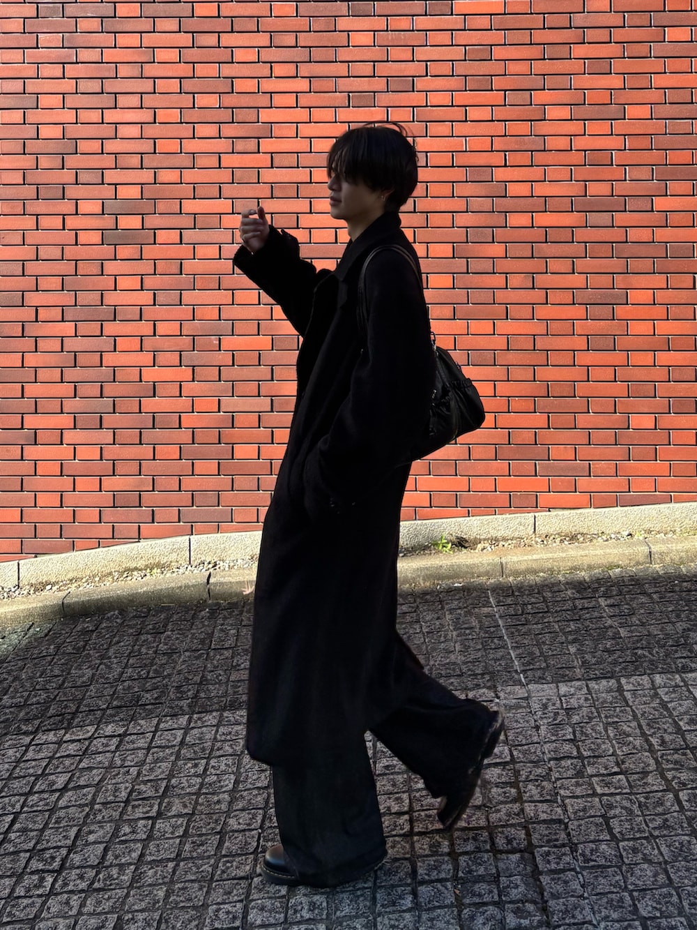 ブラック系のチェスターコート、ブラック系のデニムパンツ、ブラック系のドレスシューズを着用したメンズの冬コーディネートの2枚目の写真