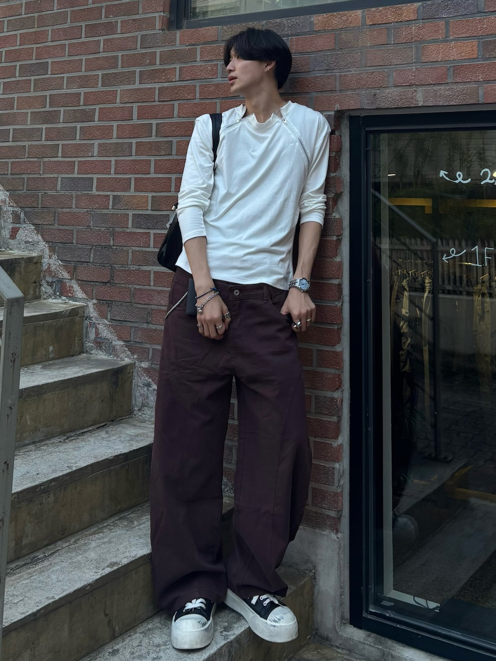 ホワイト系のTシャツ/カットソー、ブラウン系のチノパンツ、ブラック系のスニーカーを着用したメンズの夏コーディネートの2枚目の写真