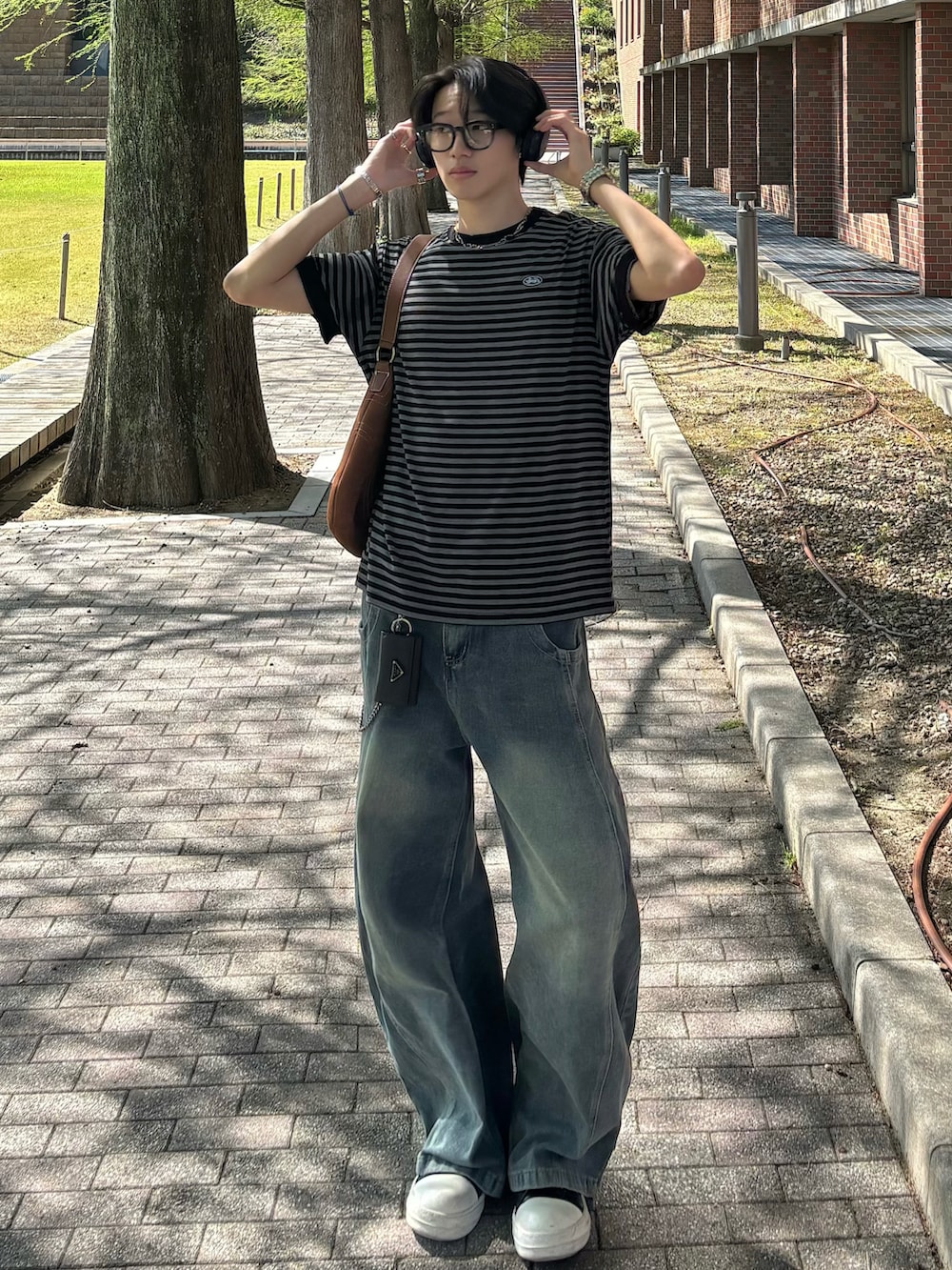 ブラック系のTシャツ/カットソー、ブルー系のデニムパンツ、ブラック系のスニーカーを着用したメンズの春コーディネートの3枚目の写真