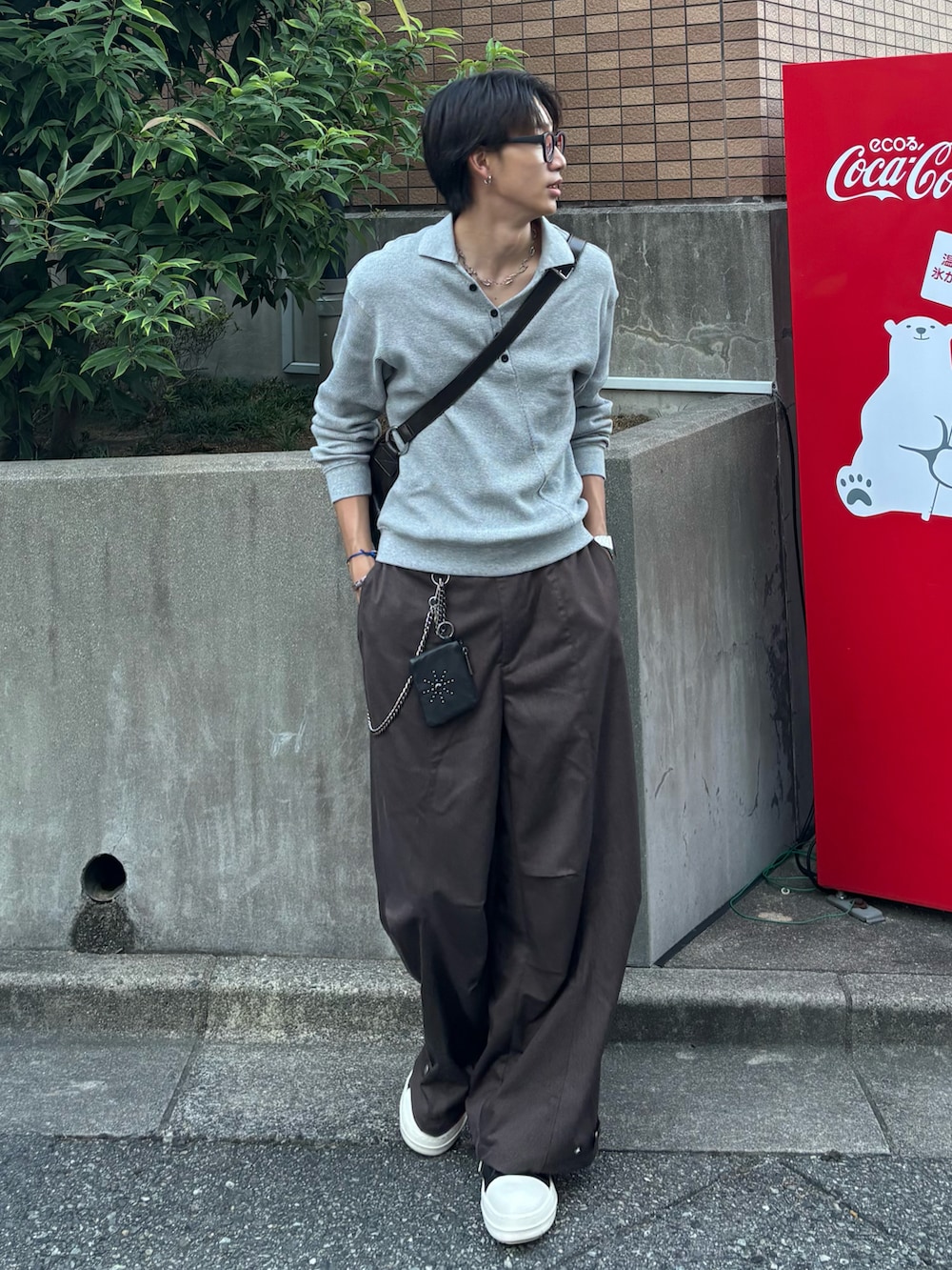 ブラウン系のスラックス、グレー系のポロシャツ、ブラウン系のショルダーバッグを着用したメンズの秋コーディネートの2枚目の写真