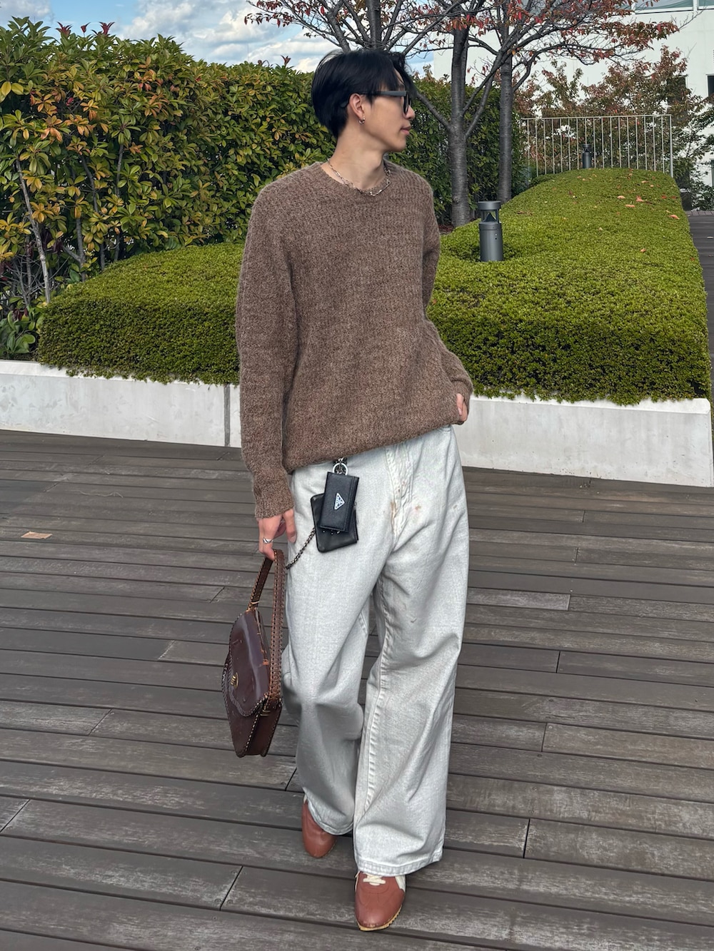 ブラウン系のニット/セーター、ホワイト系のデニムパンツ、ブラウン系のハンドバッグを着用したメンズの秋コーディネートの2枚目の写真