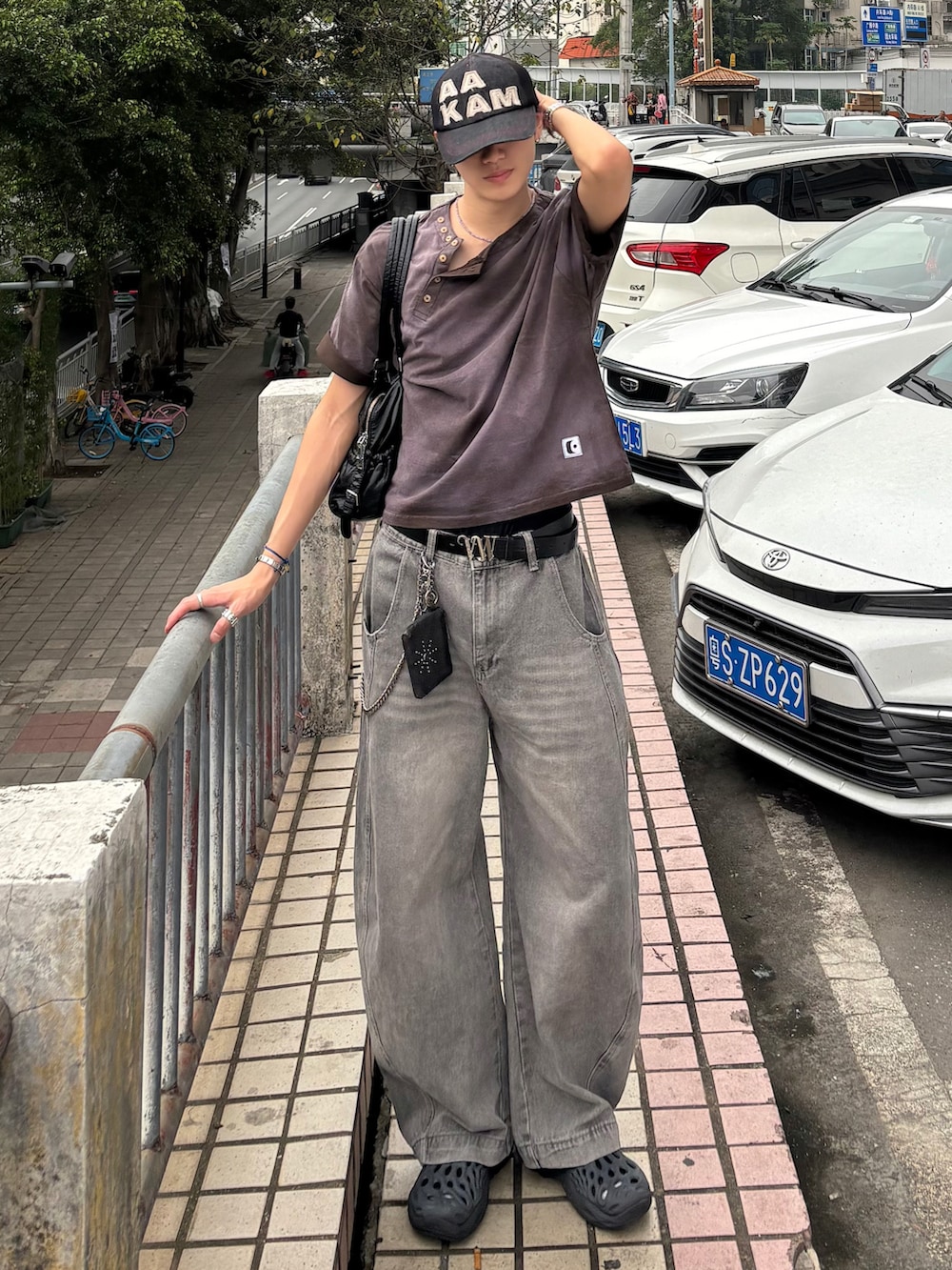 ブラウン系のTシャツ/カットソー、グレー系のデニムパンツ、ブラック系のサンダルを着用したメンズの春コーディネートの3枚目の写真