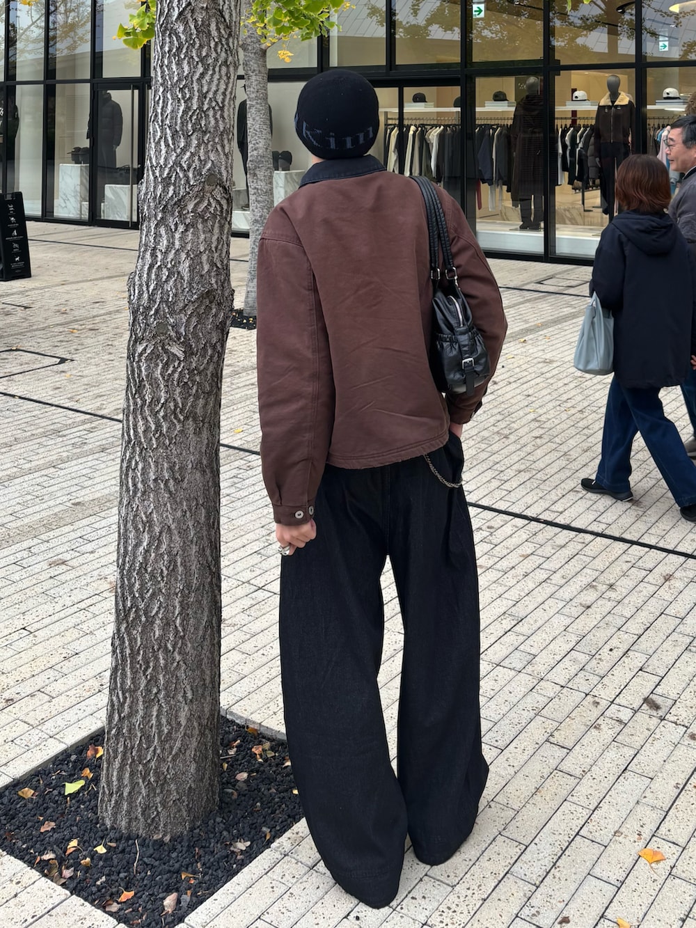 ブラウン系のブルゾン、ブラック系のデニムパンツ、ブラック系のスニーカーを着用したメンズの秋コーディネートの3枚目の写真