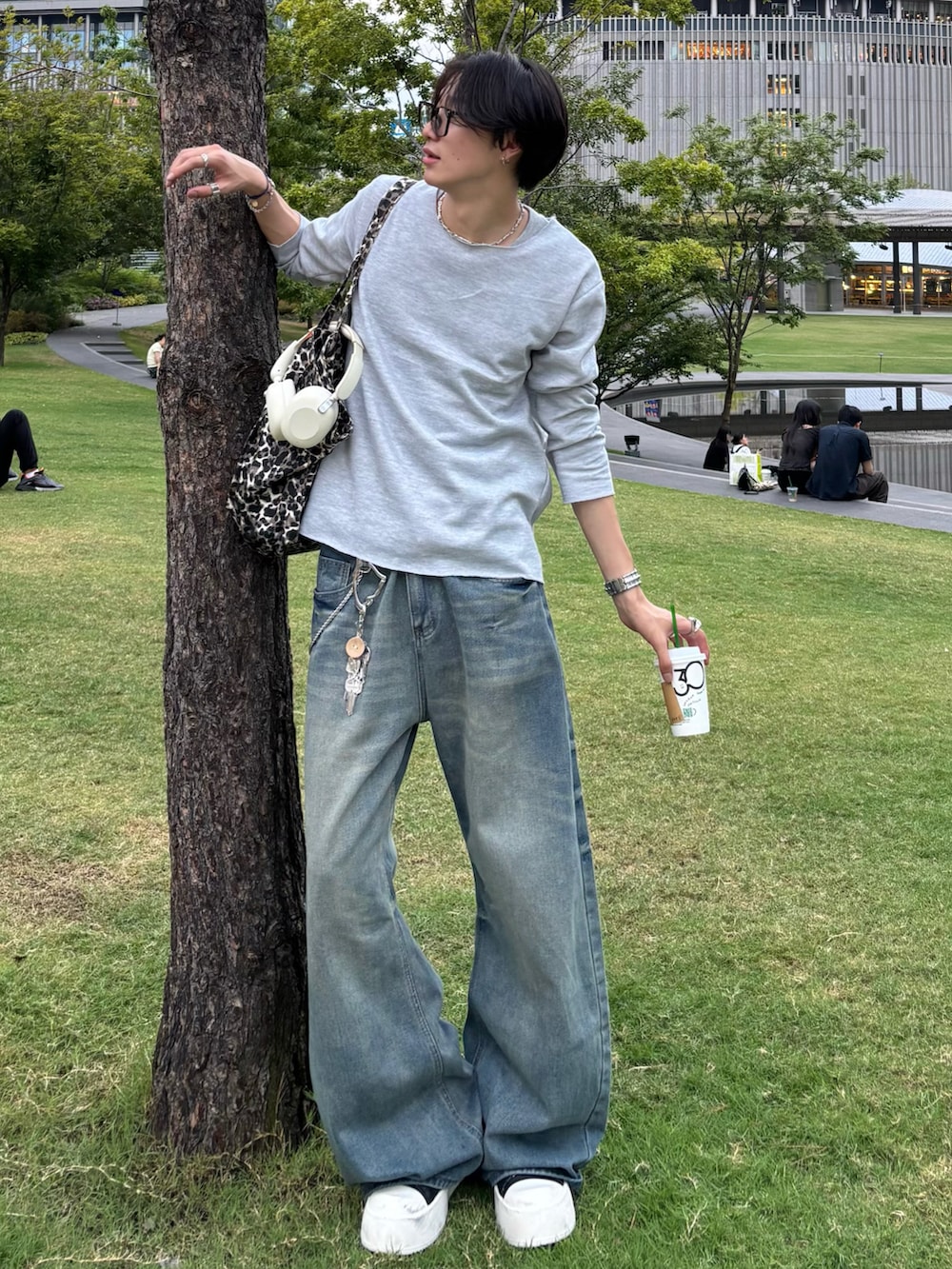 グレー系のTシャツ/カットソー、ブルー系のデニムパンツ、ブラック系のスニーカーを着用したメンズの秋コーディネートの2枚目の写真
