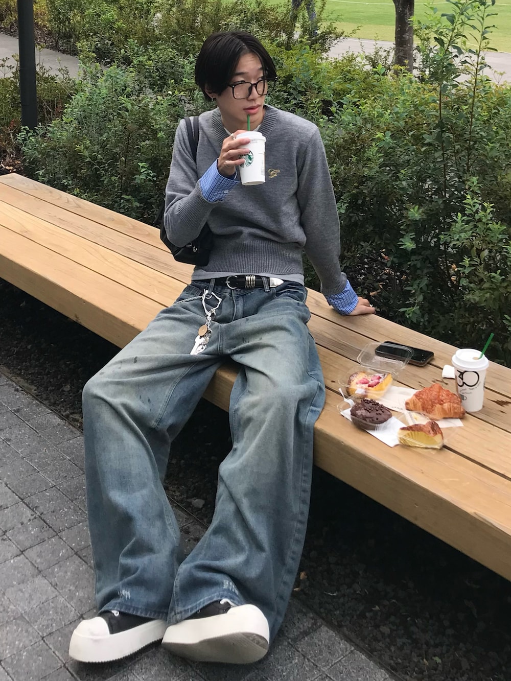 グレー系のニット/セーター、ブルー系のデニムパンツ、ブラック系のスニーカーを着用したメンズの秋コーディネートの2枚目の写真