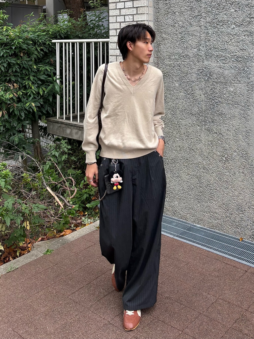 グレー系のスラックス、ブラウン系のスニーカー、ブラウン系のバッグを着用したメンズの秋コーディネートの4枚目の写真