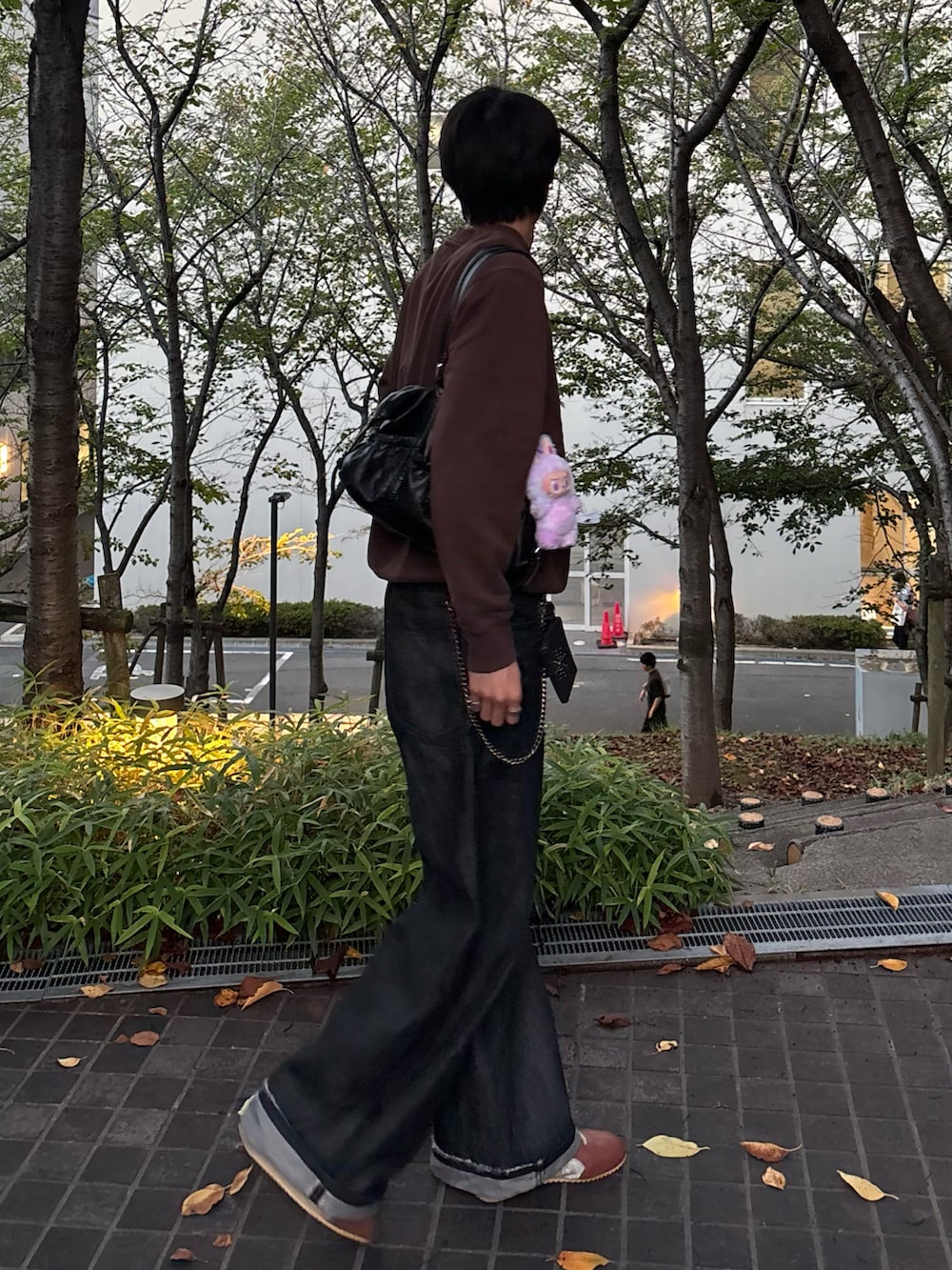 ブラック系のデニムパンツ、ブラウン系のスウェット、ブラウン系のスニーカーを着用したメンズの秋コーディネートの3枚目の写真