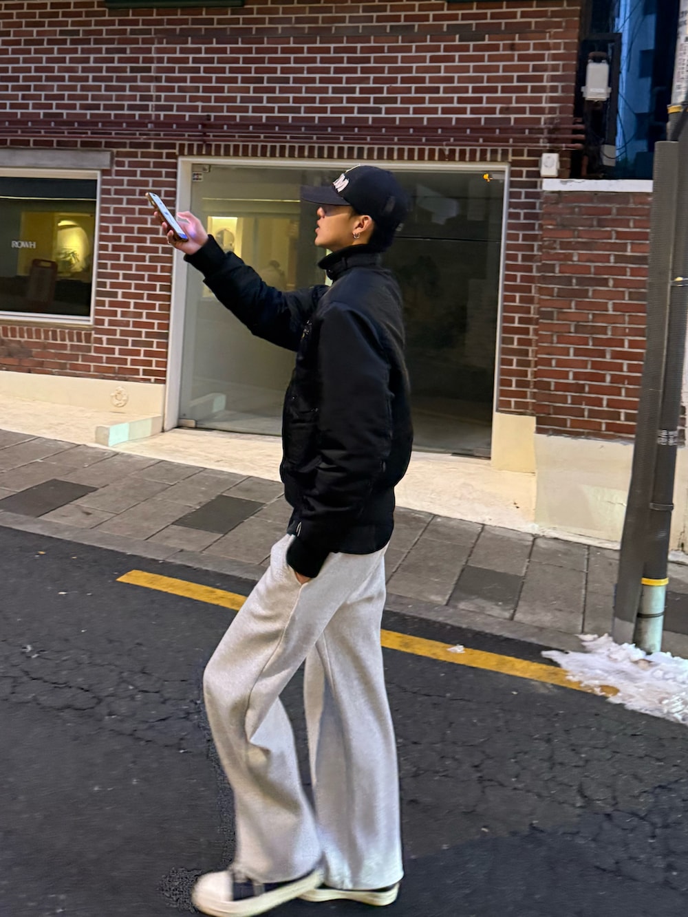 ブラウン系のショルダーバッグ、ブラック系のジャケット/アウター、グレー系のスウェットパンツを着用したメンズの冬コーディネートの2枚目の写真