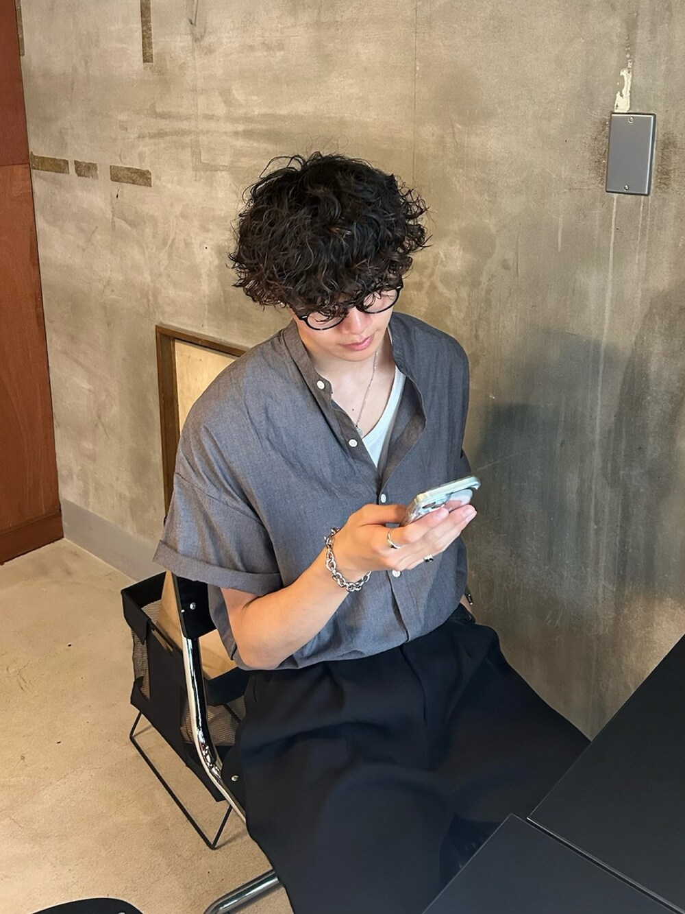 グレー系のシャツ/ブラウス、グリーン系のトートバッグ、ブラック系のスラックスを着用したメンズの春コーディネートの3枚目の写真