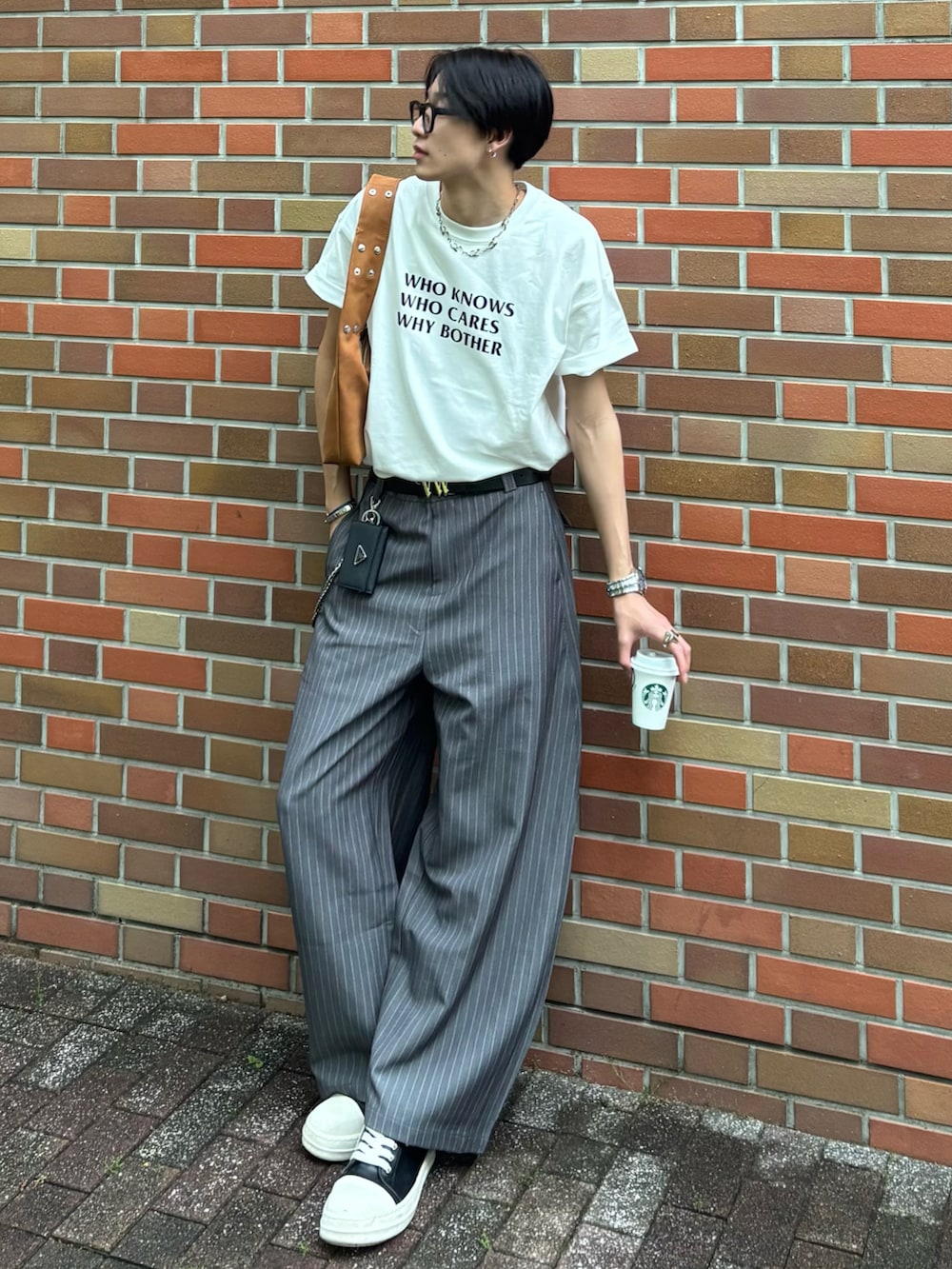 ホワイト系のTシャツ/カットソー、グレー系のスラックス、ブラック系のスニーカーを着用したメンズの春コーディネートの2枚目の写真