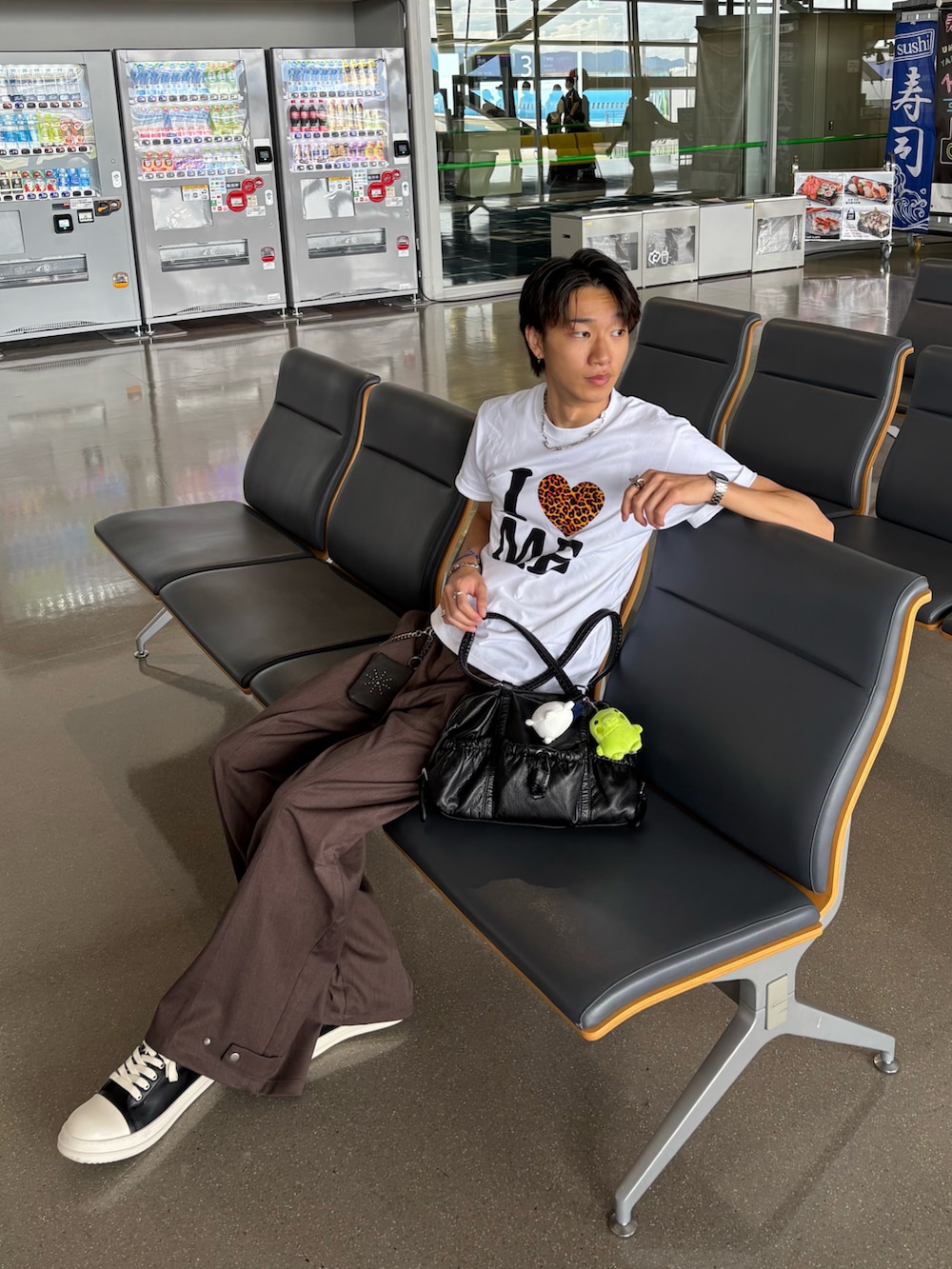 ホワイト系のTシャツ/カットソー、ブラウン系のスラックス、ブラック系のスニーカーを着用したメンズの秋コーディネートの2枚目の写真