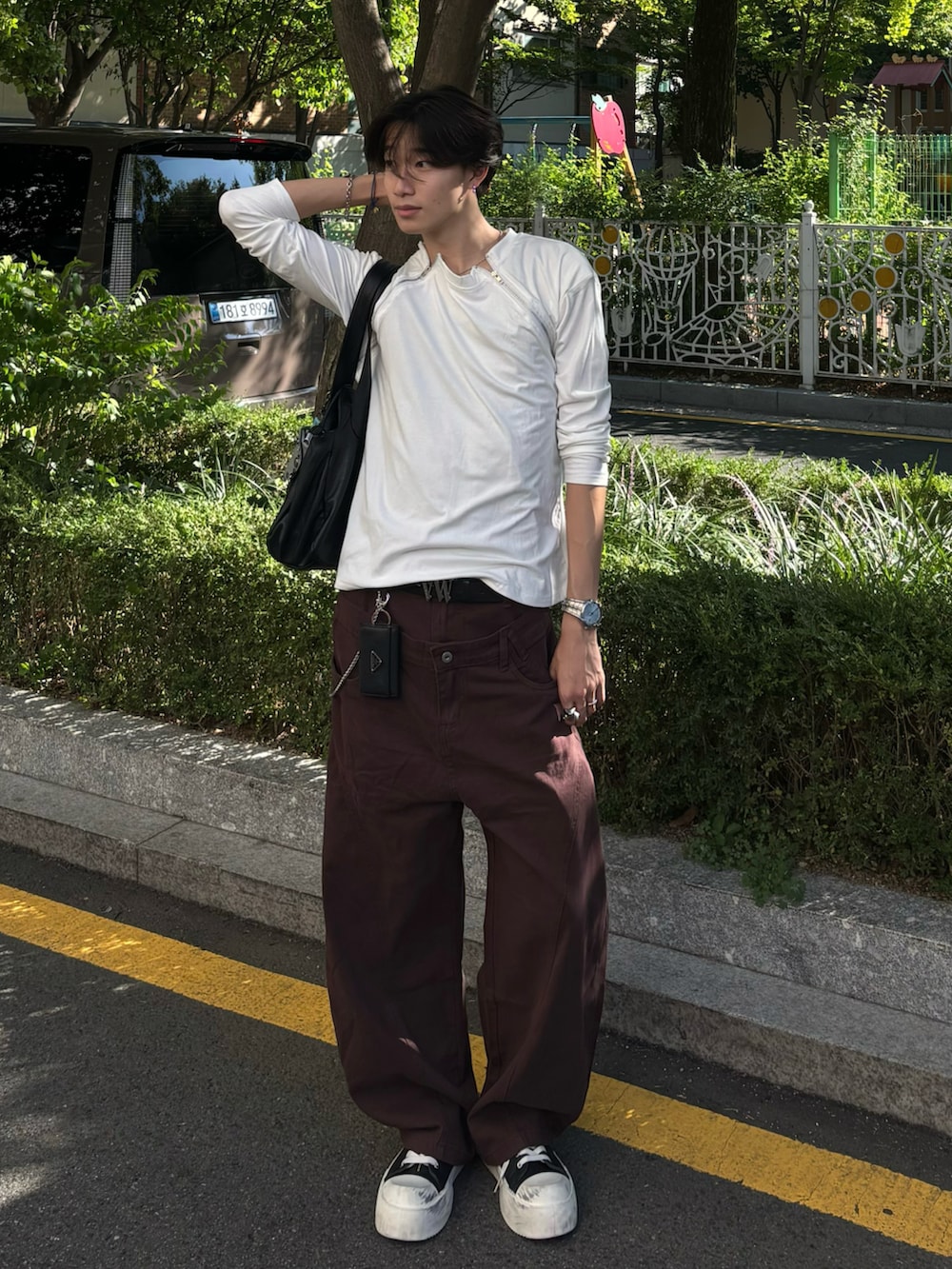 ホワイト系のTシャツ/カットソー、ブラウン系のチノパンツ、ブラック系のスニーカーを着用したメンズの夏コーディネートの3枚目の写真