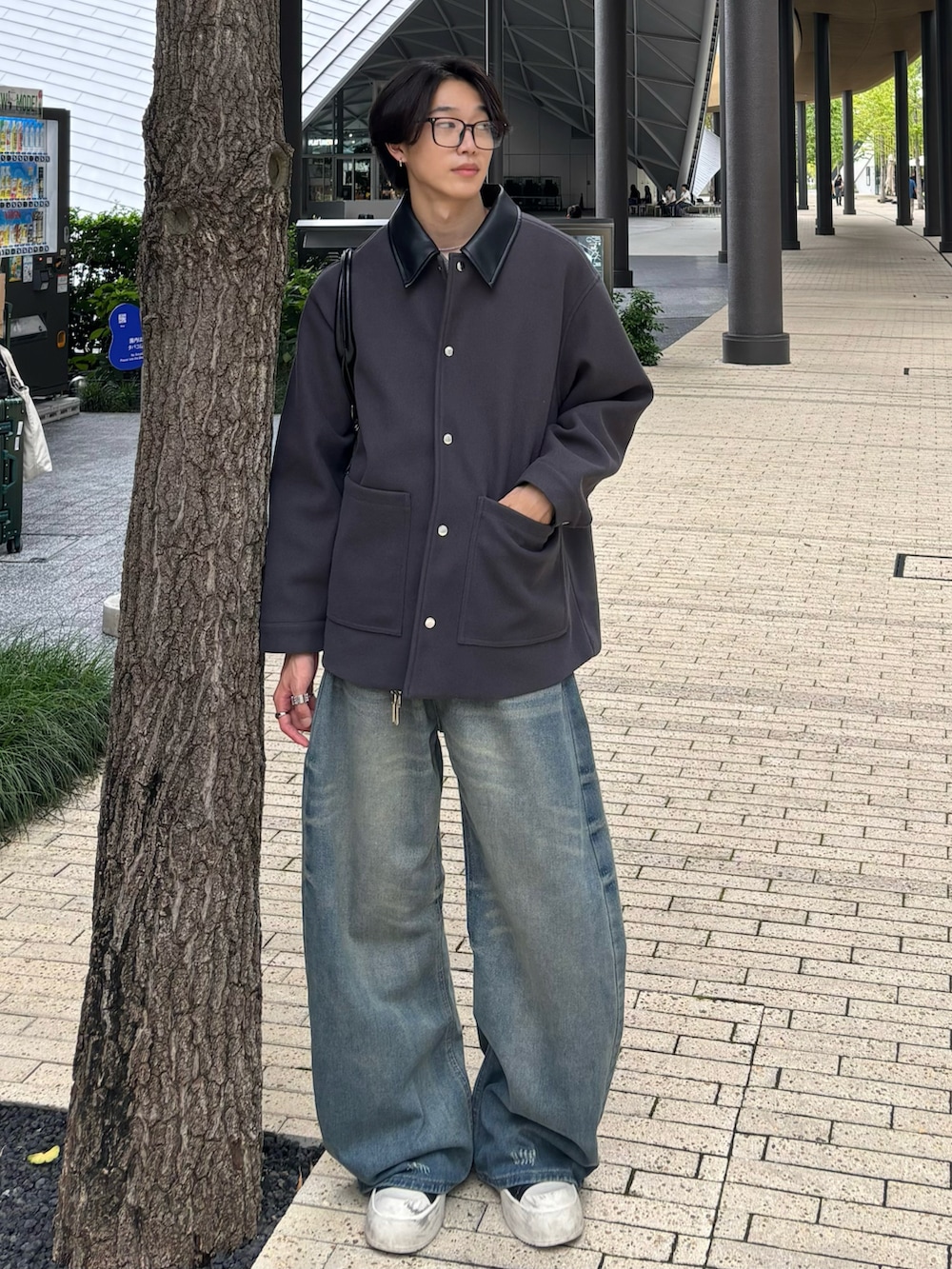 ブルー系のデニムパンツ、ブラック系のスニーカー、グレー系のステンカラーコートを着用したメンズの秋コーディネートの3枚目の写真