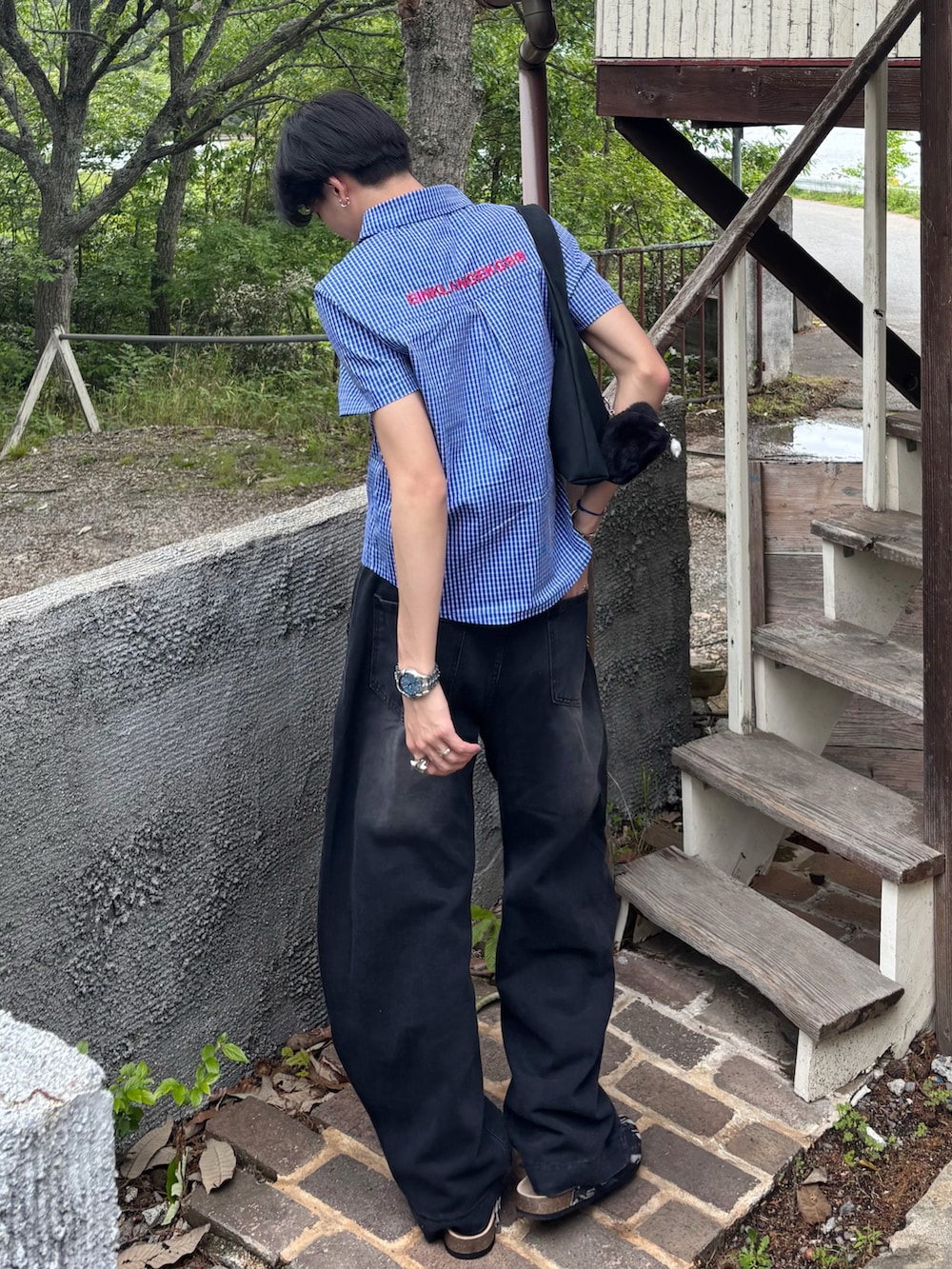ブラック系のショルダーバッグ、ブラック系のデニムパンツ、ブラック系のサンダルを着用したメンズの春コーディネートの2枚目の写真