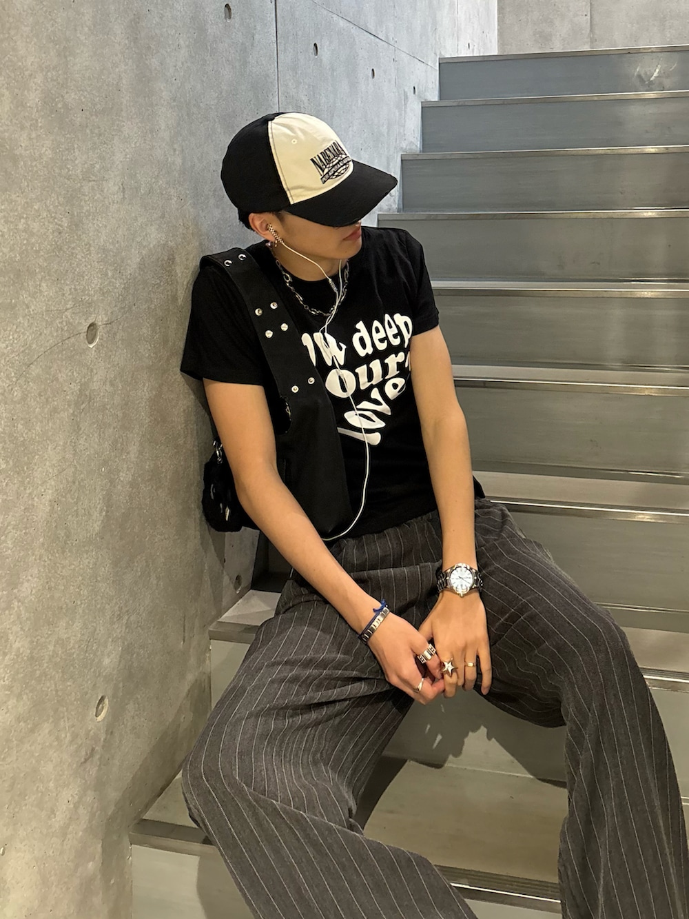 ブラック系のTシャツ/カットソー、ブラック系のショルダーバッグ、グレー系のスラックスを着用したメンズの春コーディネートの2枚目の写真