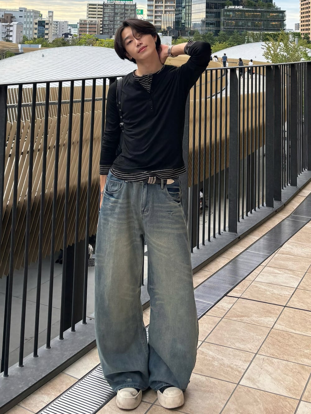 ブラック系のTシャツ/カットソー、ブルー系のデニムパンツ、ブラック系のスニーカーを着用したメンズの秋コーディネートの2枚目の写真