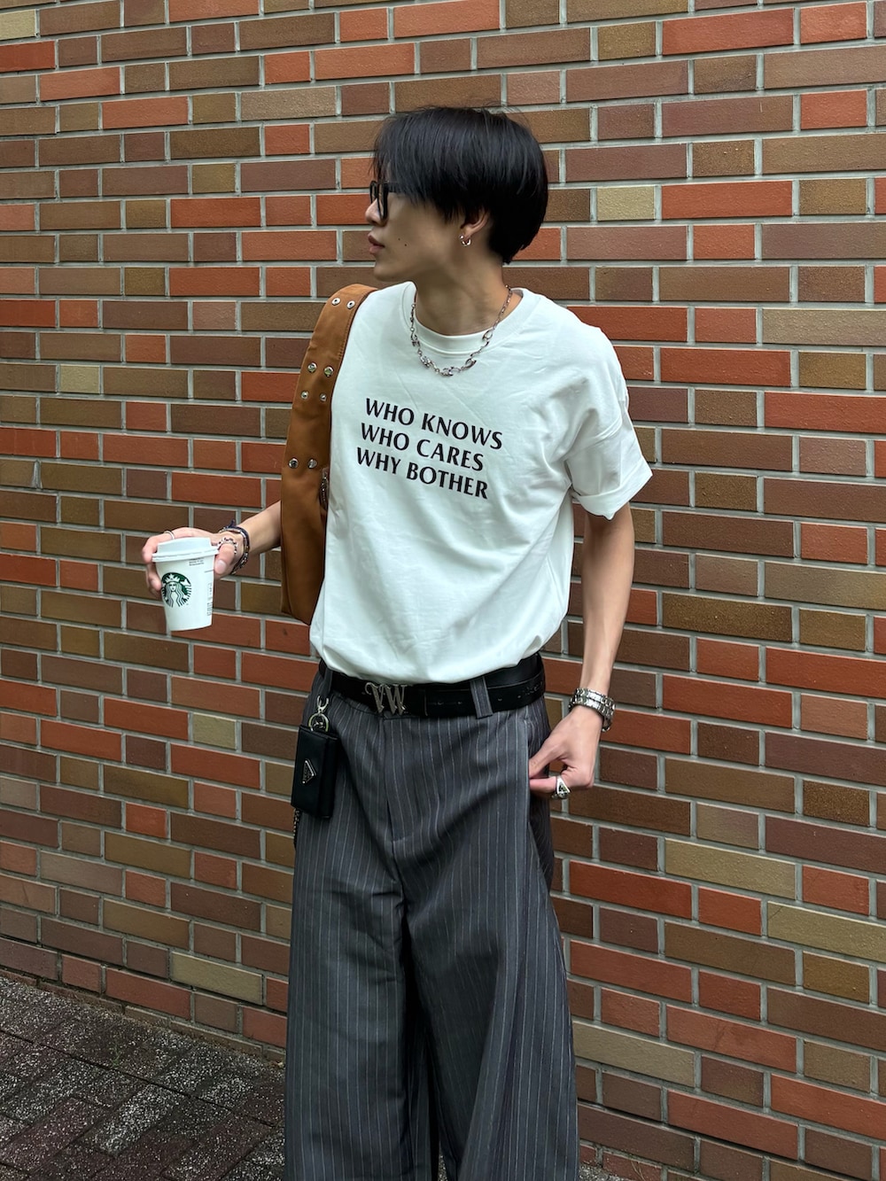 ホワイト系のTシャツ/カットソー、グレー系のスラックス、ブラック系のスニーカーを着用したメンズの春コーディネートの4枚目の写真