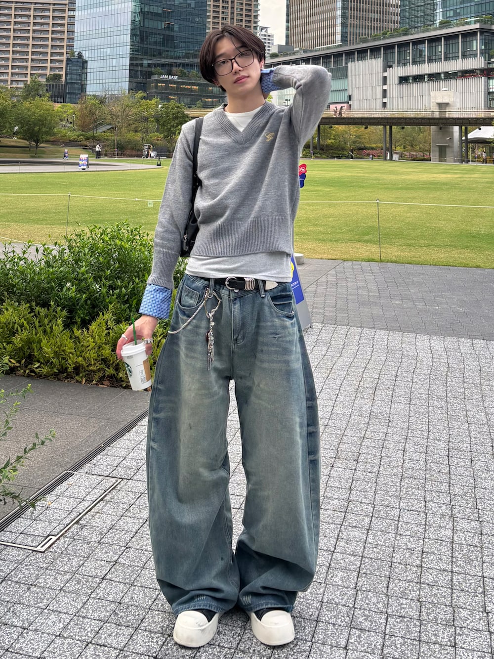 グレー系のニット/セーター、ブルー系のデニムパンツ、ブラック系のスニーカーを着用したメンズの秋コーディネートの4枚目の写真