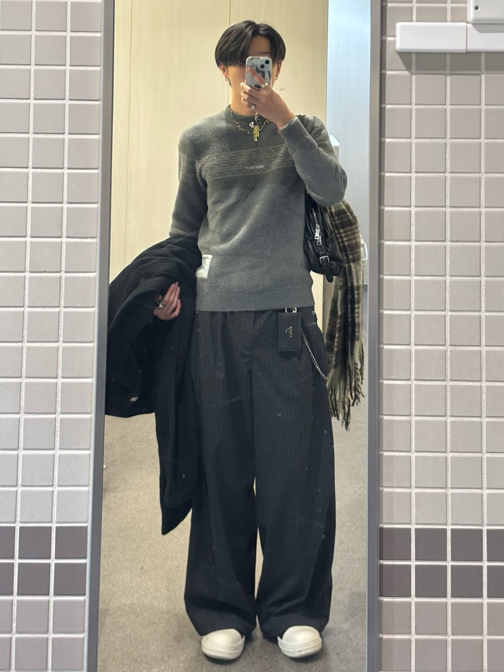 グリーン系のニット/セーター、グレー系のスラックス、ブラック系のスニーカーを着用したメンズの冬コーディネートの2枚目の写真