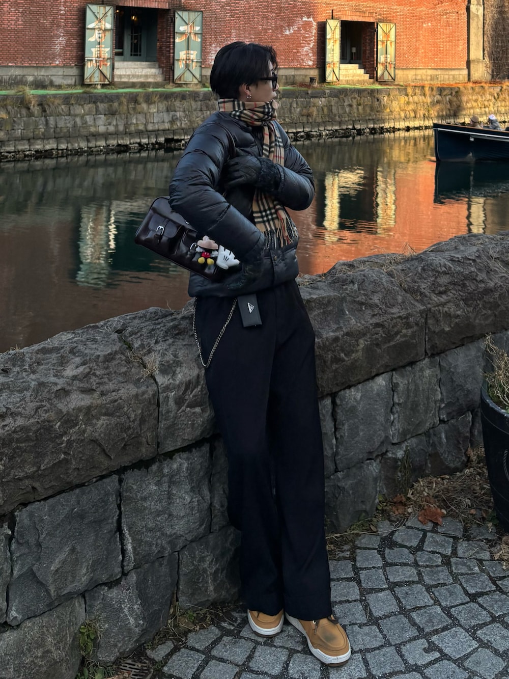 ブラウン系のショルダーバッグ、ブラック系のスラックス、イエロー系のスニーカーを着用したメンズの冬コーディネートの2枚目の写真