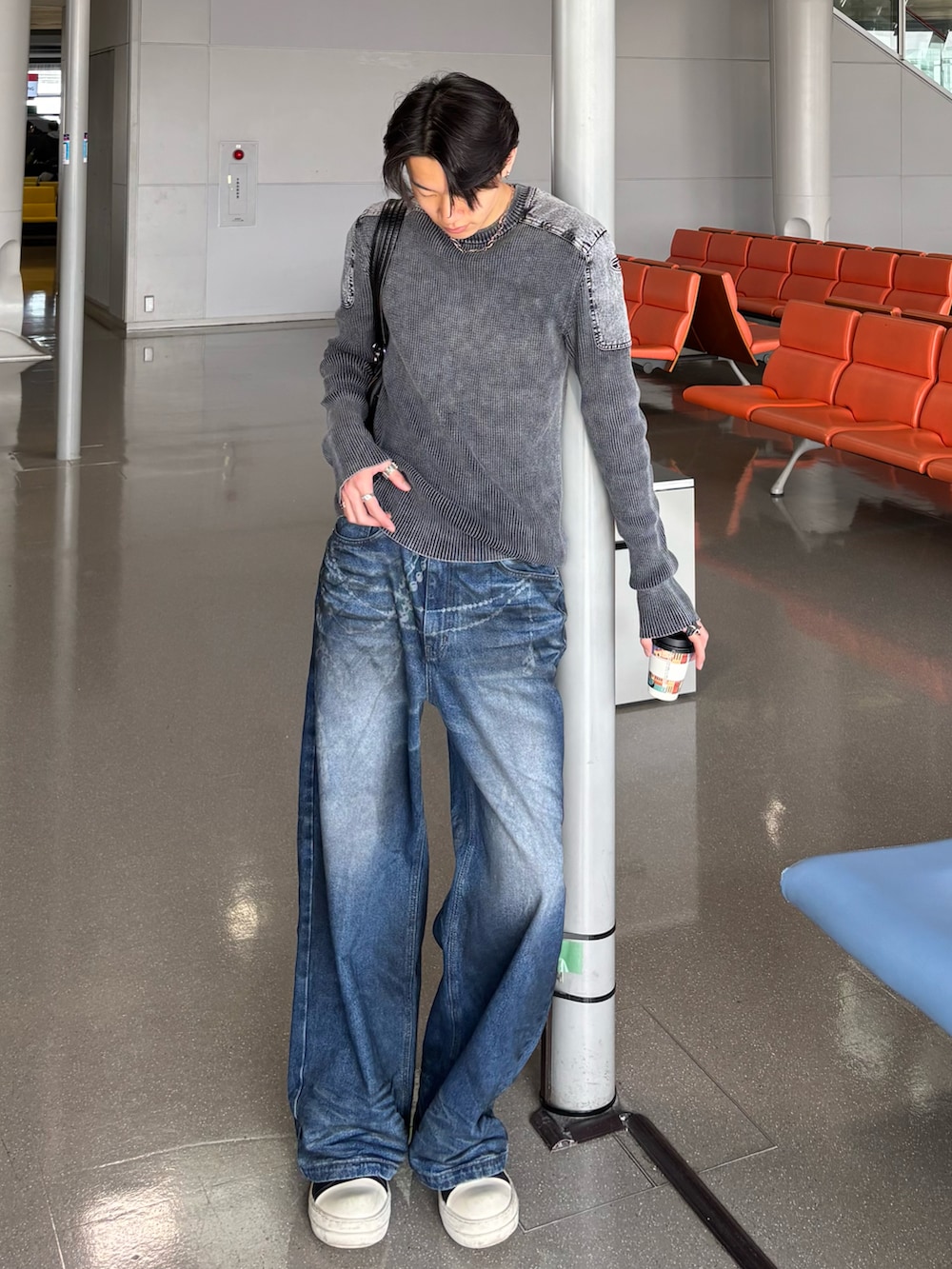 グレー系のニット/セーター、ブルー系のデニムパンツ、ブラック系のスニーカーを着用したメンズの冬コーディネートの3枚目の写真