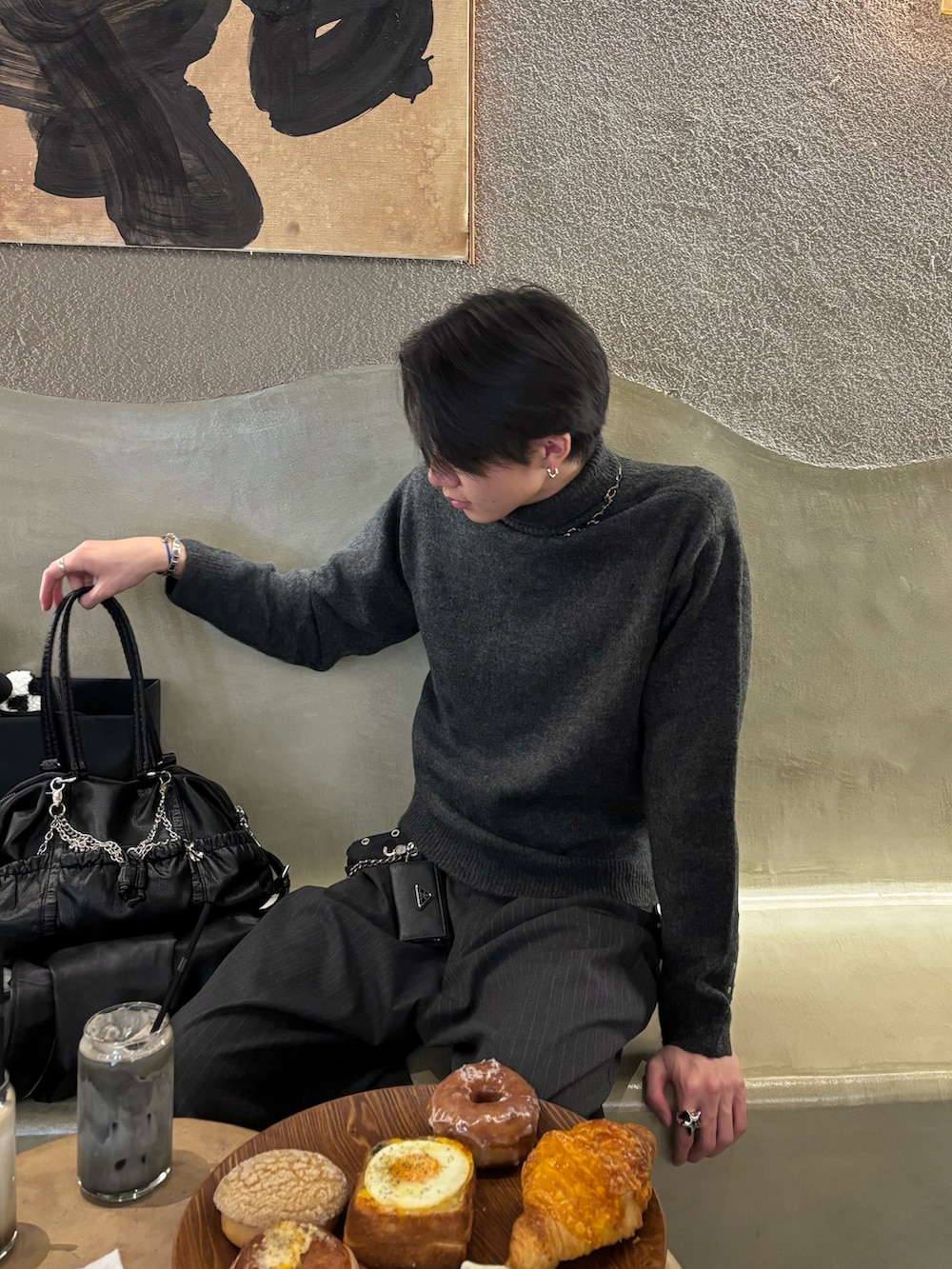 グレー系のニット/セーター、グレー系のスラックス、ブラック系のスニーカーを着用したメンズの冬コーディネートの3枚目の写真