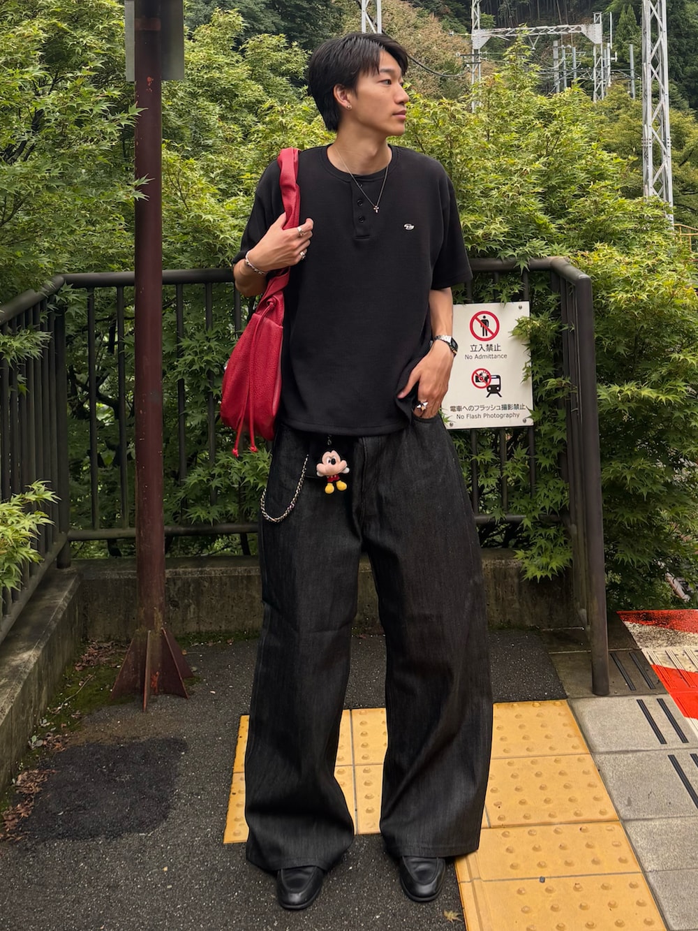 ブラック系のTシャツ/カットソー、レッド系のショルダーバッグ、ブラック系のデニムパンツを着用したメンズの夏コーディネートの2枚目の写真