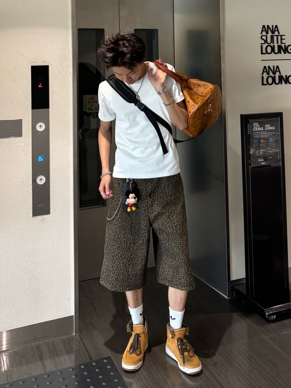 ホワイト系のTシャツ/カットソー、ブラウン系のデニムパンツ、ベージュ系のスニーカーを着用したメンズの夏コーディネートの2枚目の写真