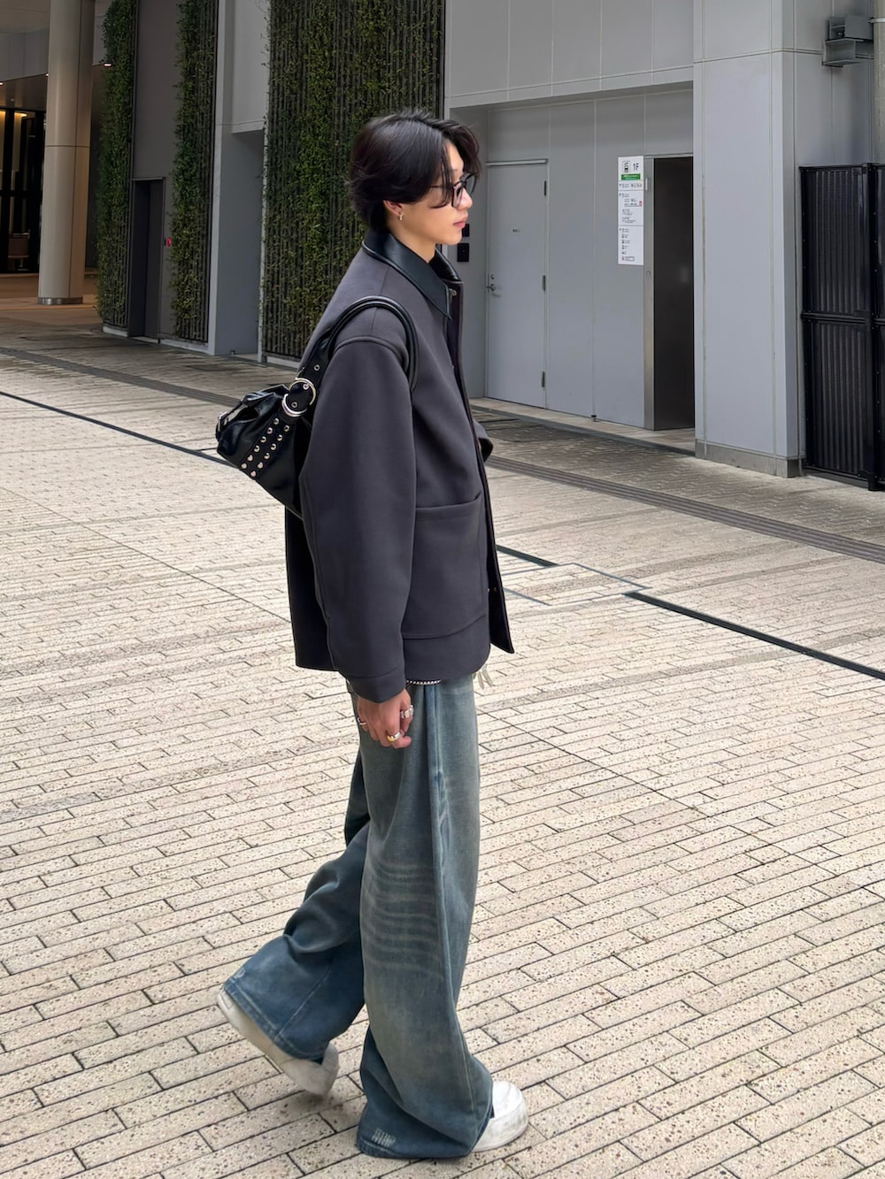 ブルー系のデニムパンツ、ブラック系のスニーカー、グレー系のステンカラーコートを着用したメンズの秋コーディネートの4枚目の写真