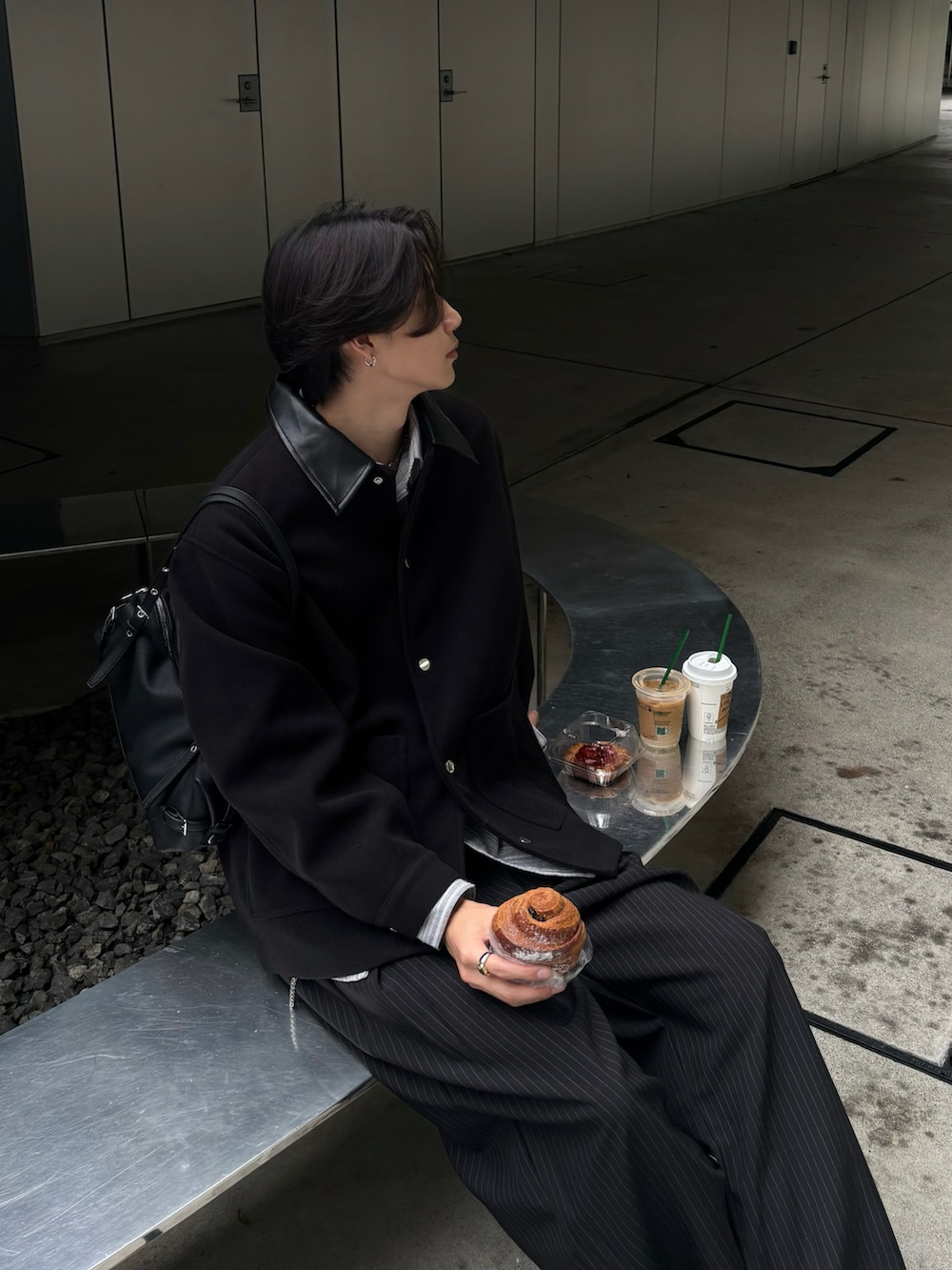 ブラック系のステンカラーコート、ブラック系のスラックス、ブラック系のスニーカーを着用したメンズの秋コーディネートの5枚目の写真