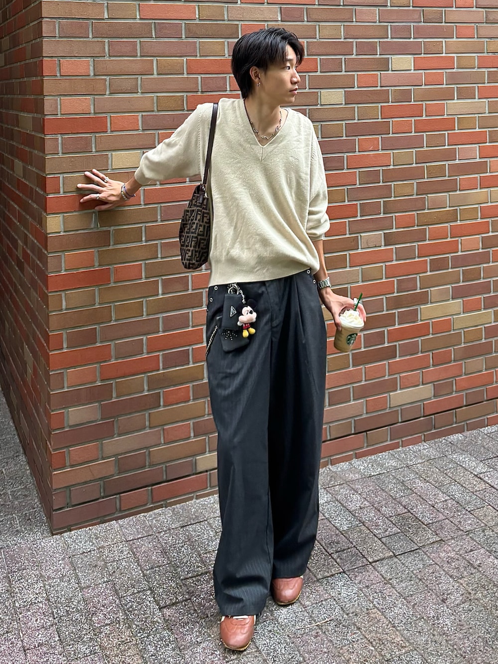 グレー系のスラックス、ブラウン系のスニーカー、ブラウン系のバッグを着用したメンズの秋コーディネートの2枚目の写真