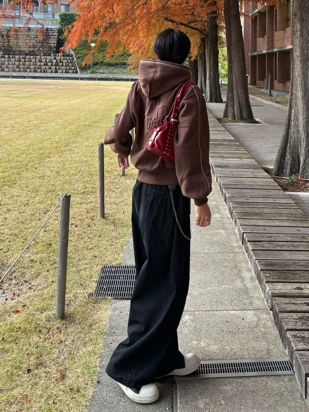 ブラック系のデニムパンツ、ブラック系のスニーカー、ブラウン系のパーカーを着用したメンズの秋コーディネートの2枚目の写真