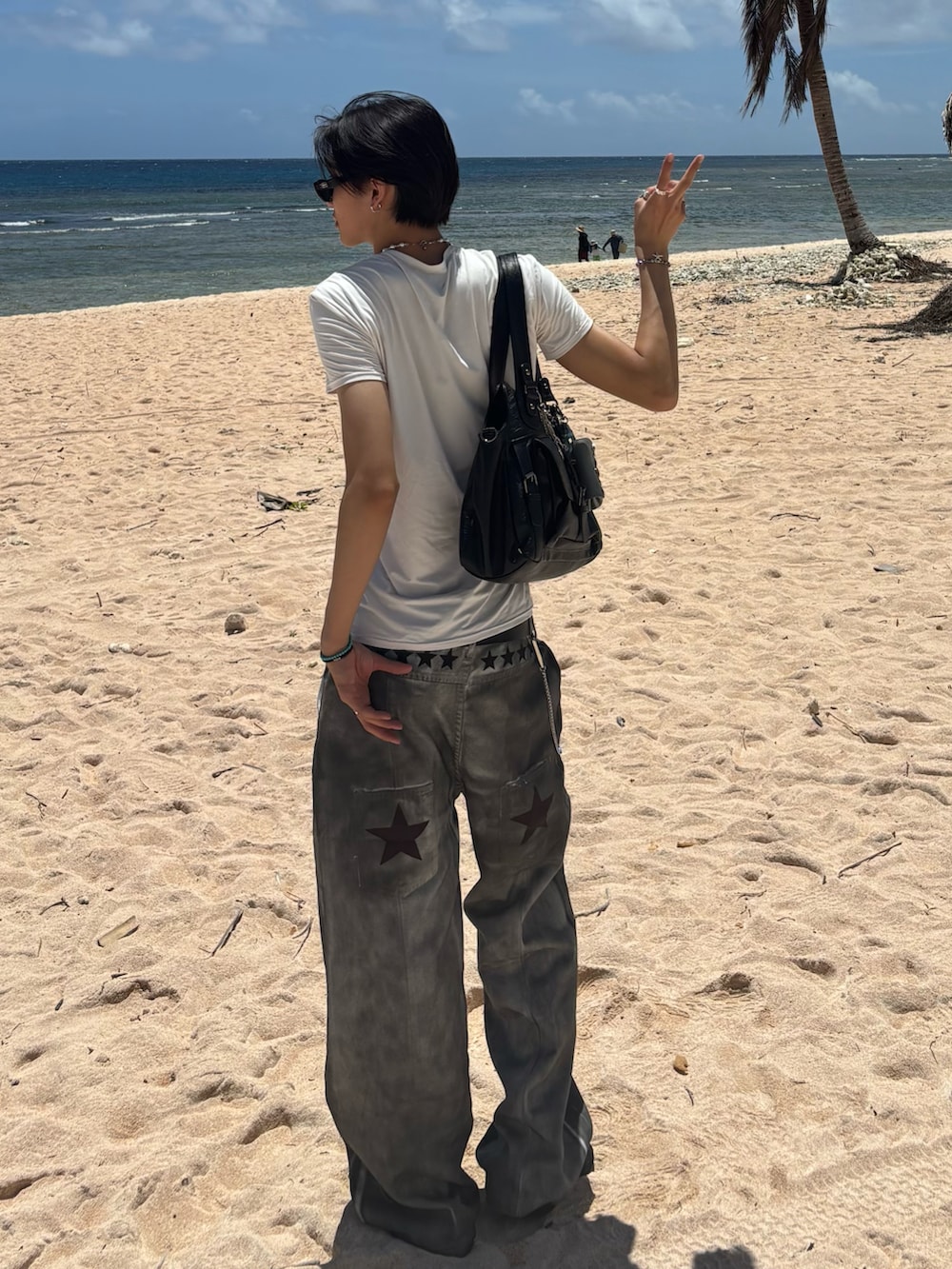 ホワイト系のデニムパンツ、ブラック系のサンダル、ホワイト系のラッシュガードを着用したメンズの夏コーディネートの4枚目の写真