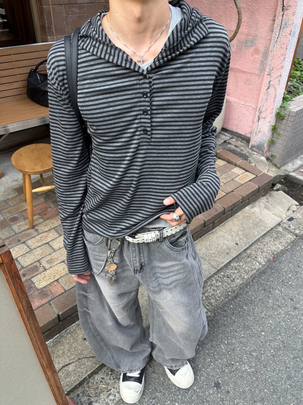 ブラック系のパーカー、ブラック系のショルダーバッグ、グレー系のデニムパンツを着用したメンズの秋コーディネートの5枚目の写真