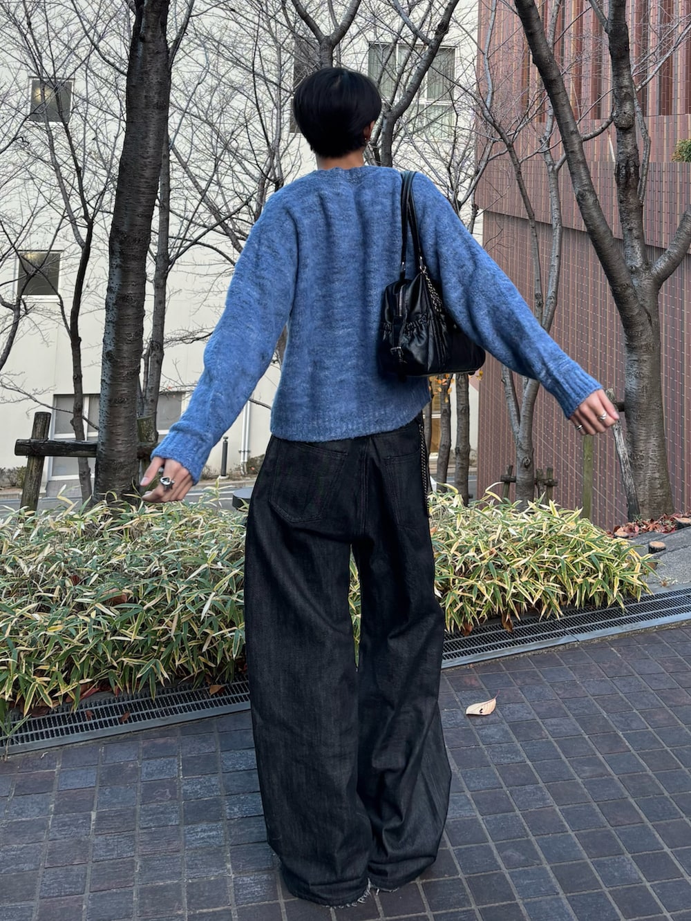 ブルー系のニット/セーター、ブラック系のデニムパンツ、ブラック系のスニーカーを着用したメンズの冬コーディネートの3枚目の写真