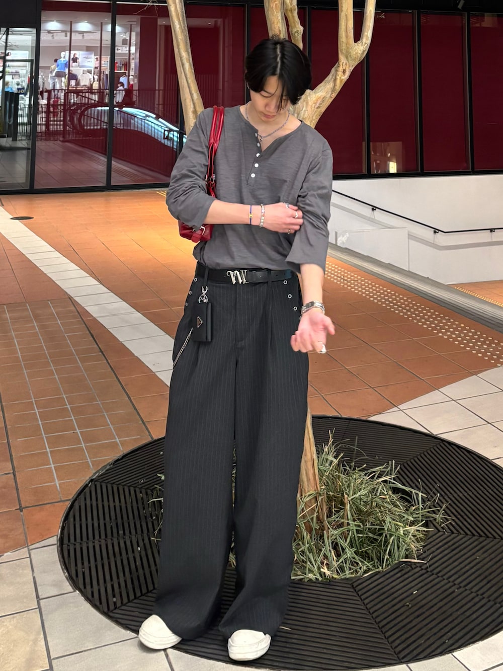 ホワイト系のTシャツ/カットソー、グレー系のスラックス、ブラック系のスニーカーを着用したメンズの春コーディネートの2枚目の写真
