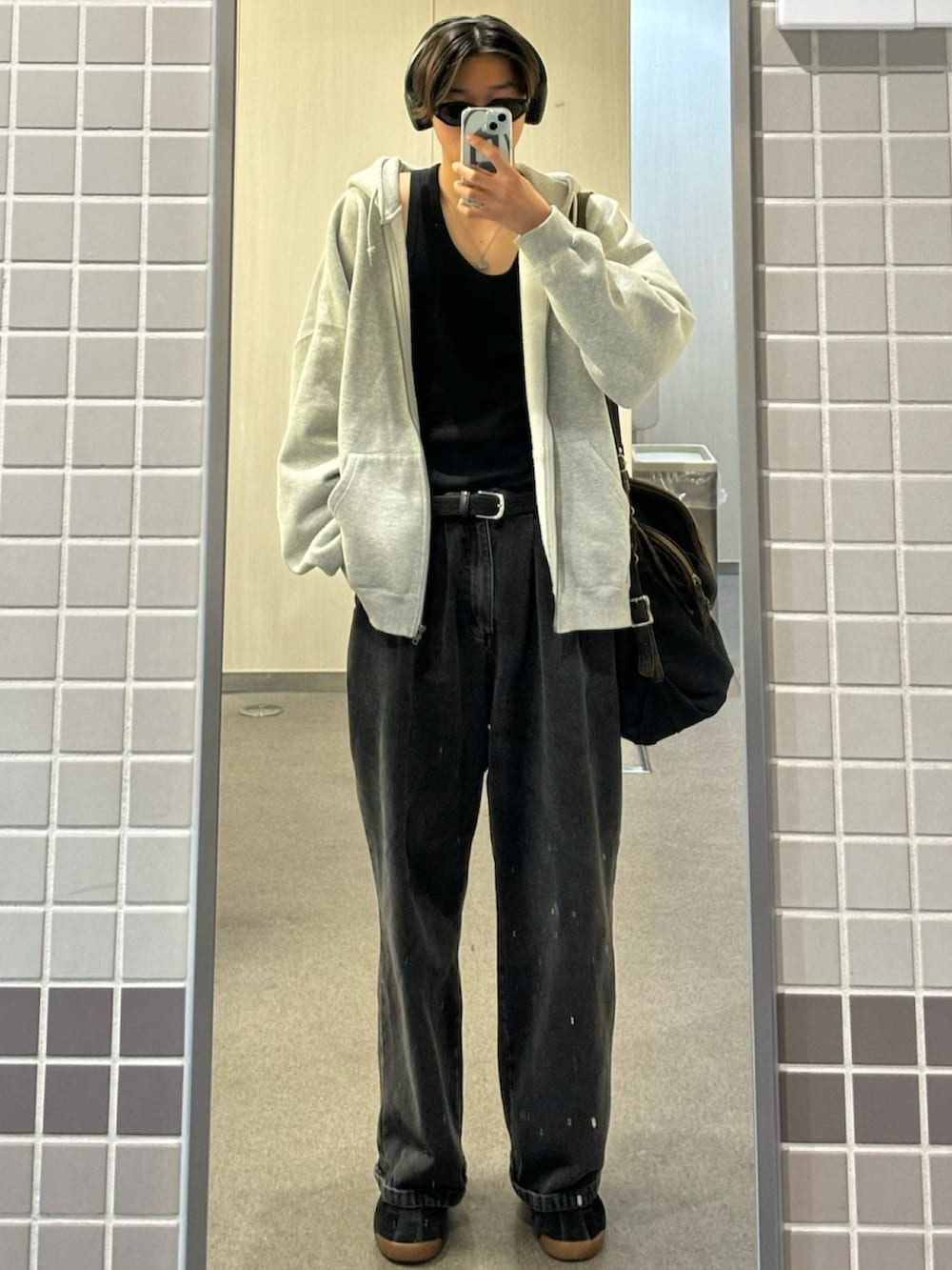グレー系のパーカー、ブラック系のデニムパンツ、ブラック系のスニーカーを着用したメンズの春コーディネートの2枚目の写真