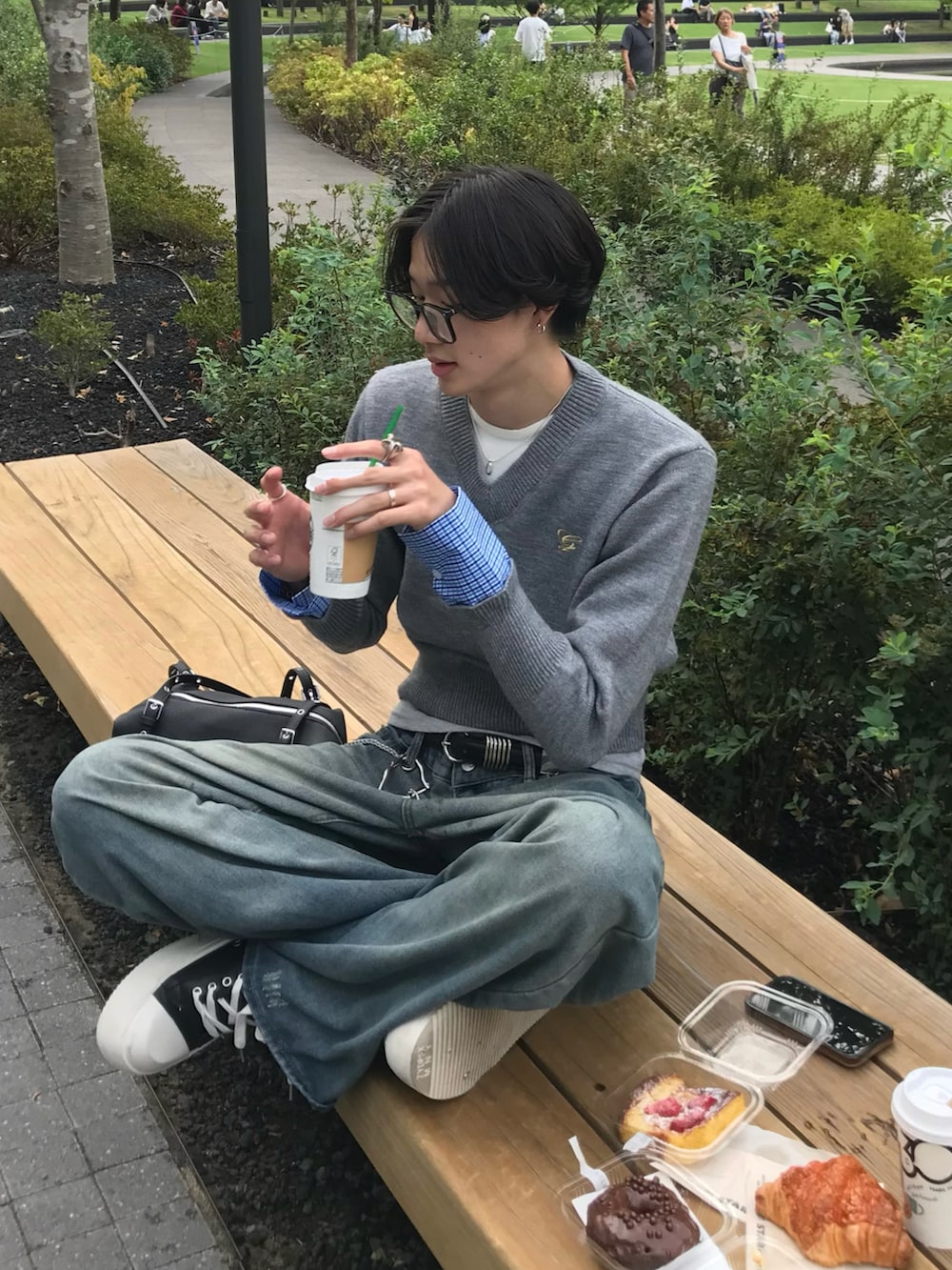 グレー系のニット/セーター、ブルー系のデニムパンツ、ブラック系のスニーカーを着用したメンズの秋コーディネートの3枚目の写真