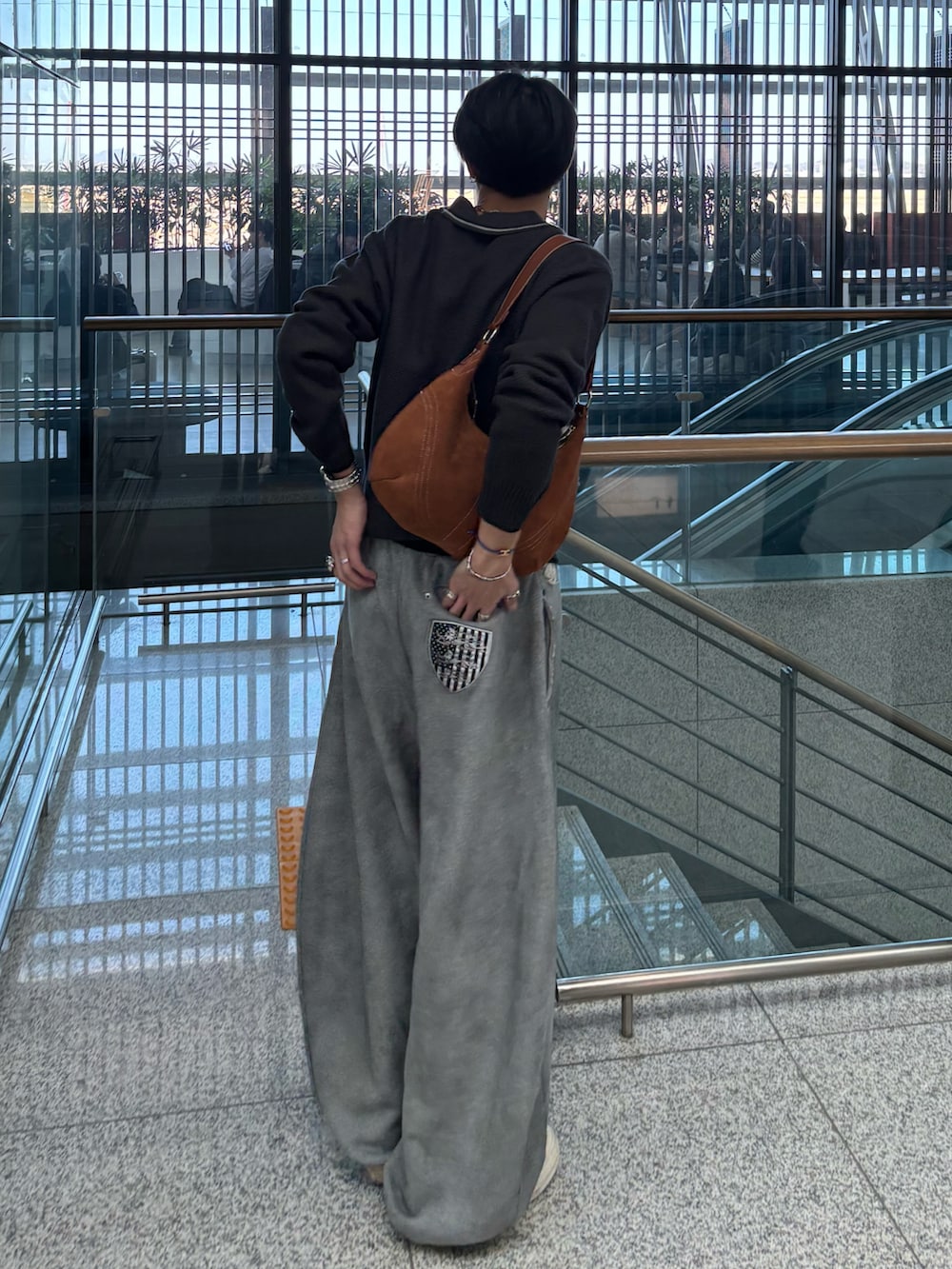 グレー系のポロシャツ、ブラウン系のショルダーバッグ、グレー系のスウェットパンツを着用したメンズの冬コーディネートの2枚目の写真