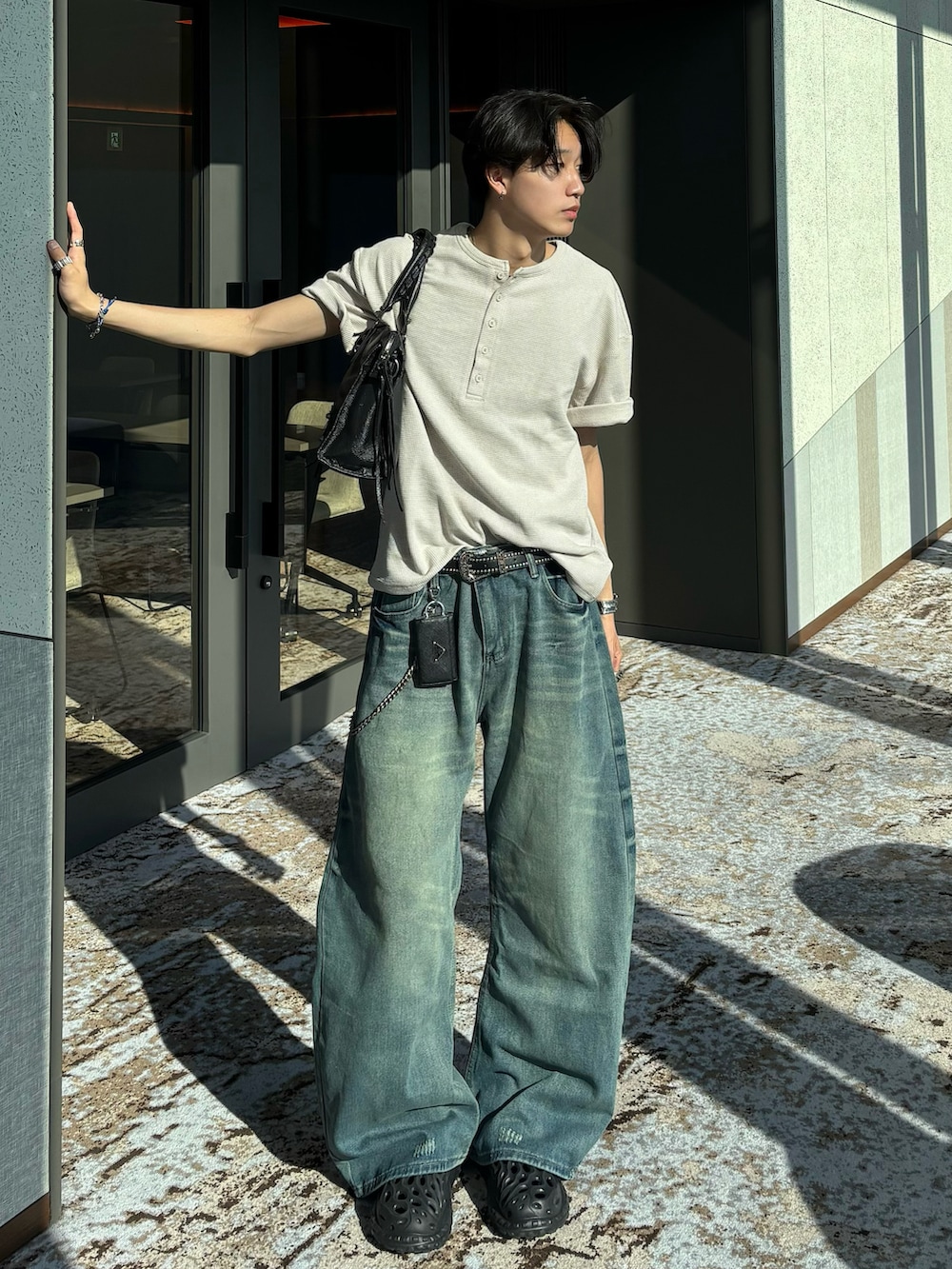 ベージュ系のTシャツ/カットソー、ブルー系のデニムパンツ、ブラック系のショルダーバッグを着用したメンズの春コーディネートの2枚目の写真