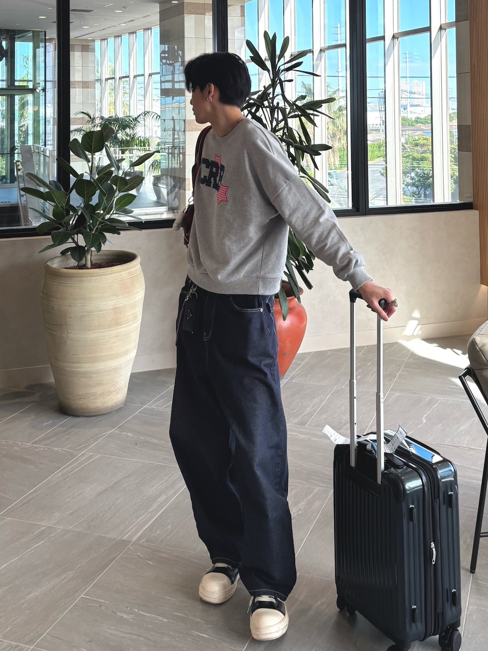 グレー系のスウェット、ブルー系のデニムパンツ、ブラック系のスニーカーを着用したメンズの秋コーディネートの2枚目の写真