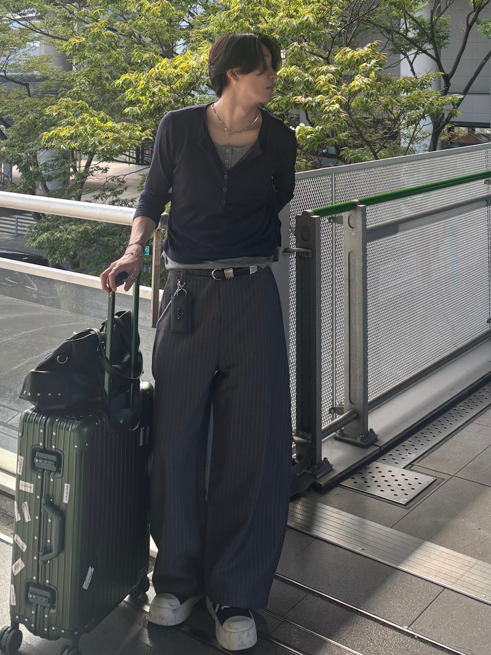 ブルー系のTシャツ/カットソー、グレー系のスラックス、ブラック系のスニーカーを着用したメンズの秋コーディネートの4枚目の写真