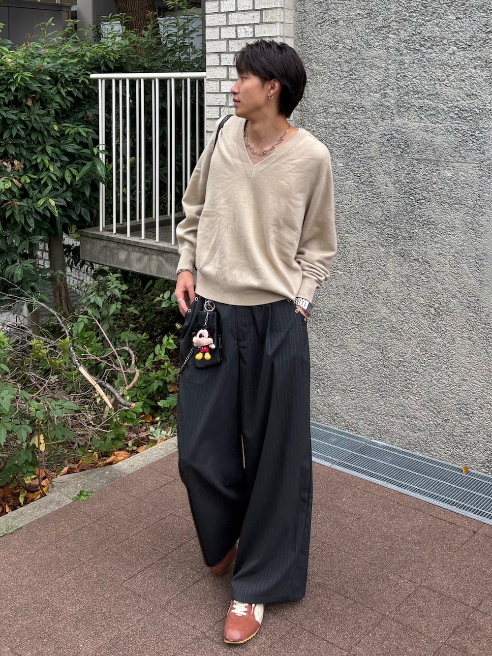 グレー系のスラックス、ブラウン系のスニーカー、ブラウン系のバッグを着用したメンズの秋コーディネートの3枚目の写真